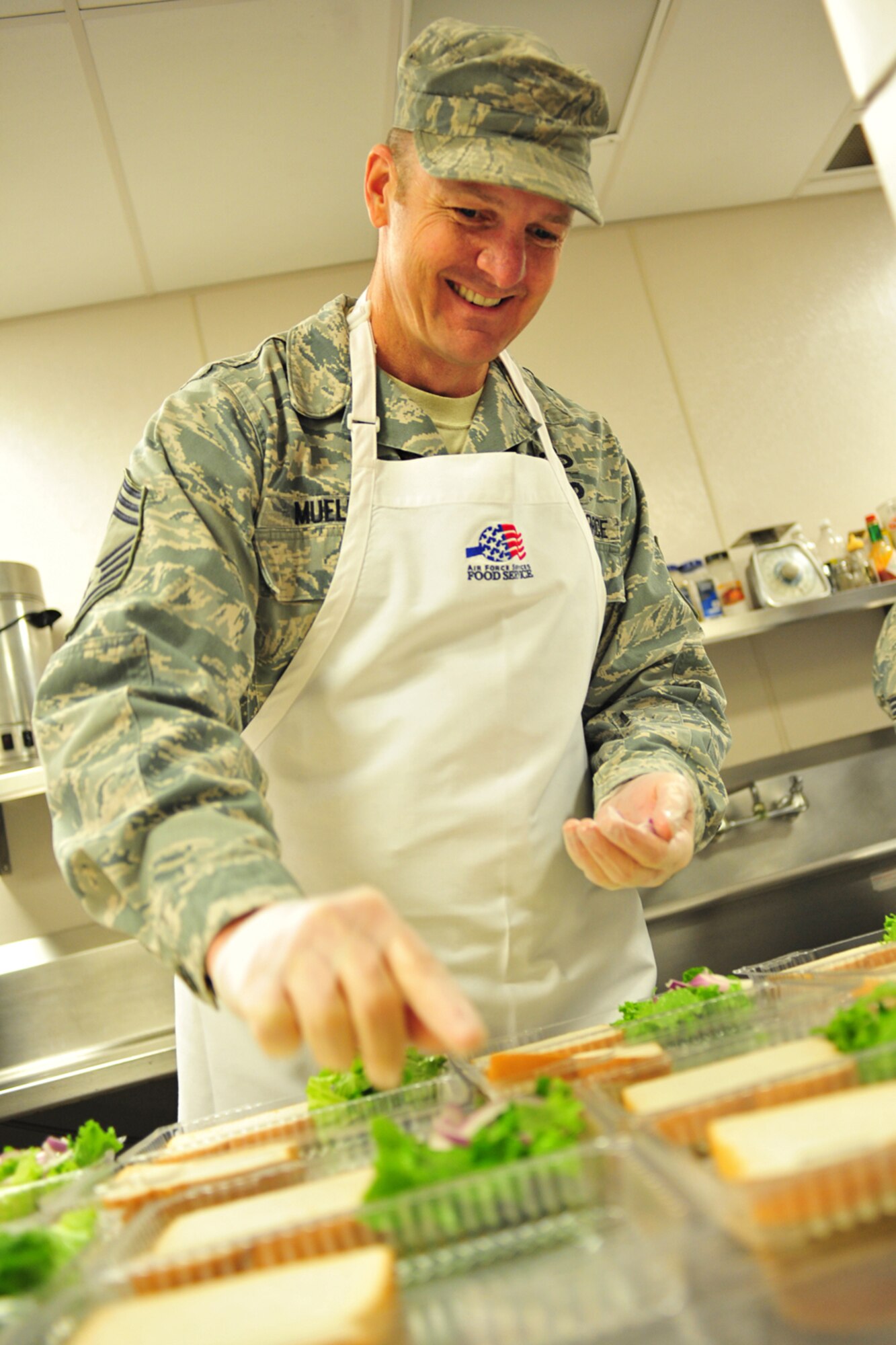 Chief Master Sgt. Robert Mueller, 92nd Mission Support Group, assists the dining facility staff by making sandwiches for boxed lunches at Fairchild Air Force Base, Wash., Oct. 31, 2013. The boxed lunches are prepared for flyers, security forces and maintenance workers that don’t normally have enough time to stop for a meal. (U.S. Air Force photo by Senior Airman Taylor Curry/Released)