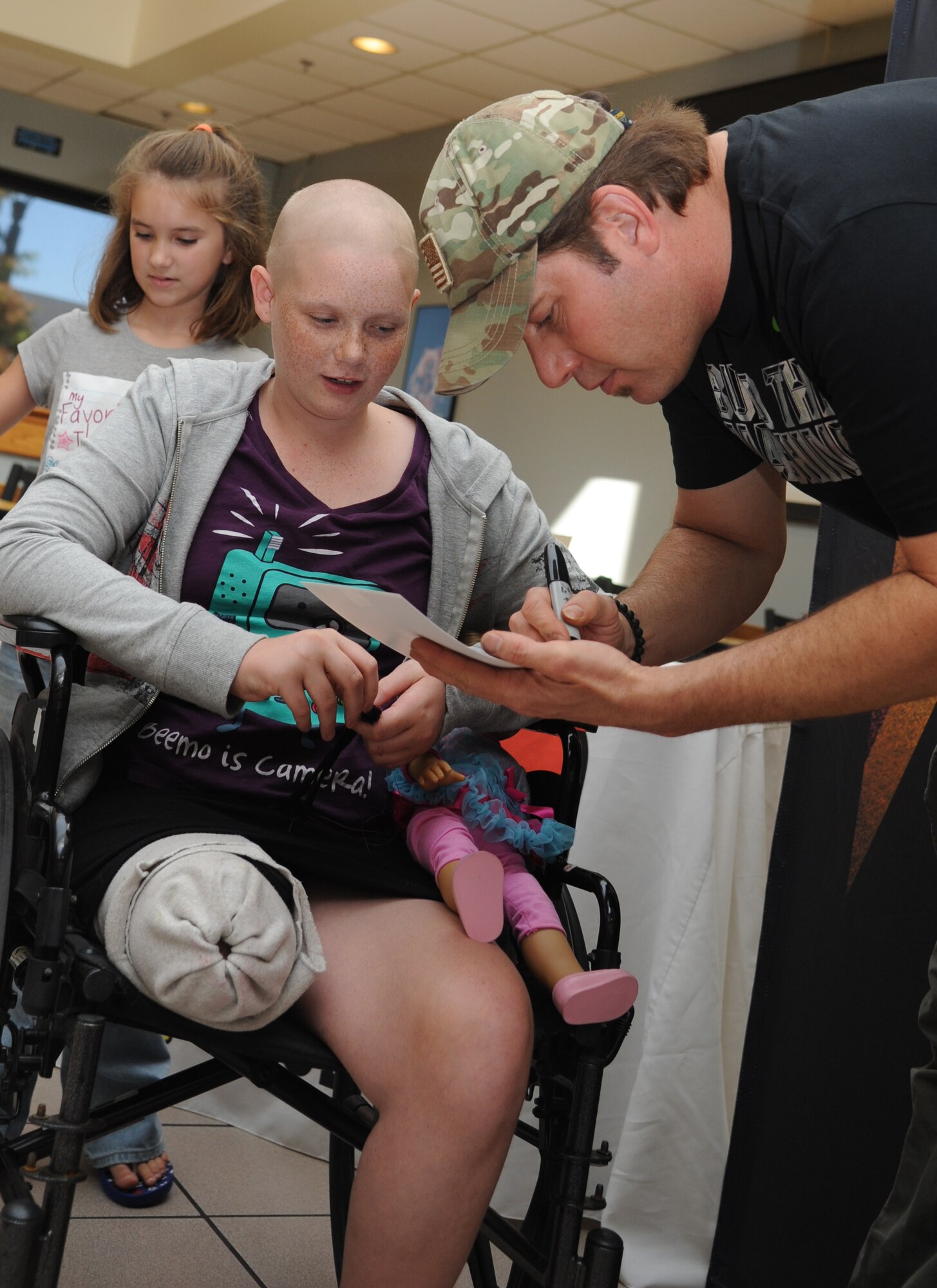 Rodney Atkins, country music singer, autographs a self-portrait for the nieces of Robyn Curry, 81st Medical Operations Squadron, during a meet and greet session following a concert performed by Atkins Nov. 2, 2013, at the Magnolia Dining Facility, Keesler Air Force Base, Miss.  Local band Autumn Rise-N also performed.  (U.S. Air Force photo by Kemberly Groue)