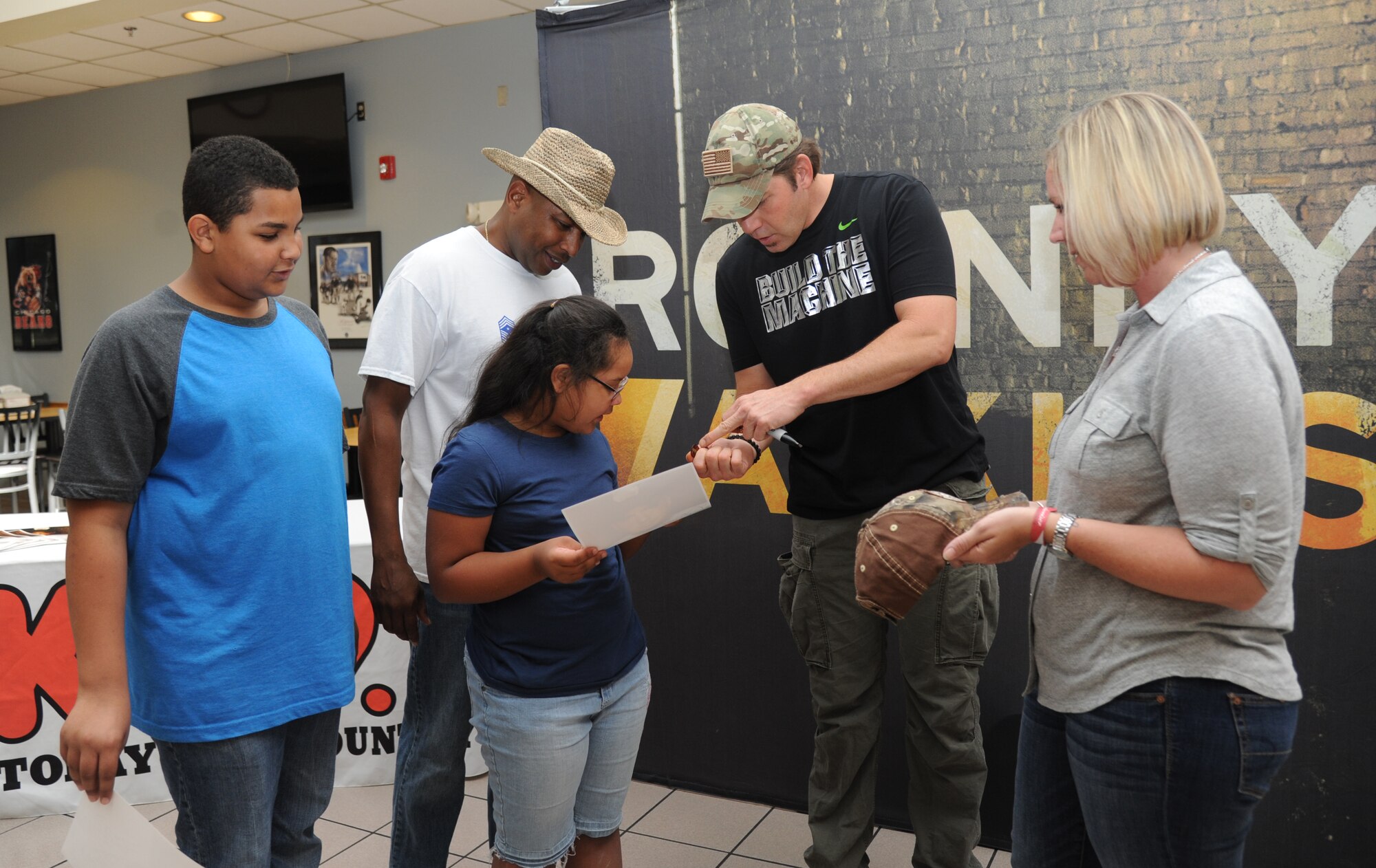 Rodney Atkins, country music singer, gives an autographed guitar pick to the children of Chief Master Sgt. Farrell Thomas, 81st Training Wing command chief, and Senior Master Sgt. Lisa Thomas, 81st Force Support Squadron, during a meet and greet session following a concert performed by Atkins Nov. 2, 2013, at the Magnolia Dining Facility, Keesler Air Force Base, Miss.  Local band Autumn Rise-N also performed.  (U.S. Air Force photo by Kemberly Groue)