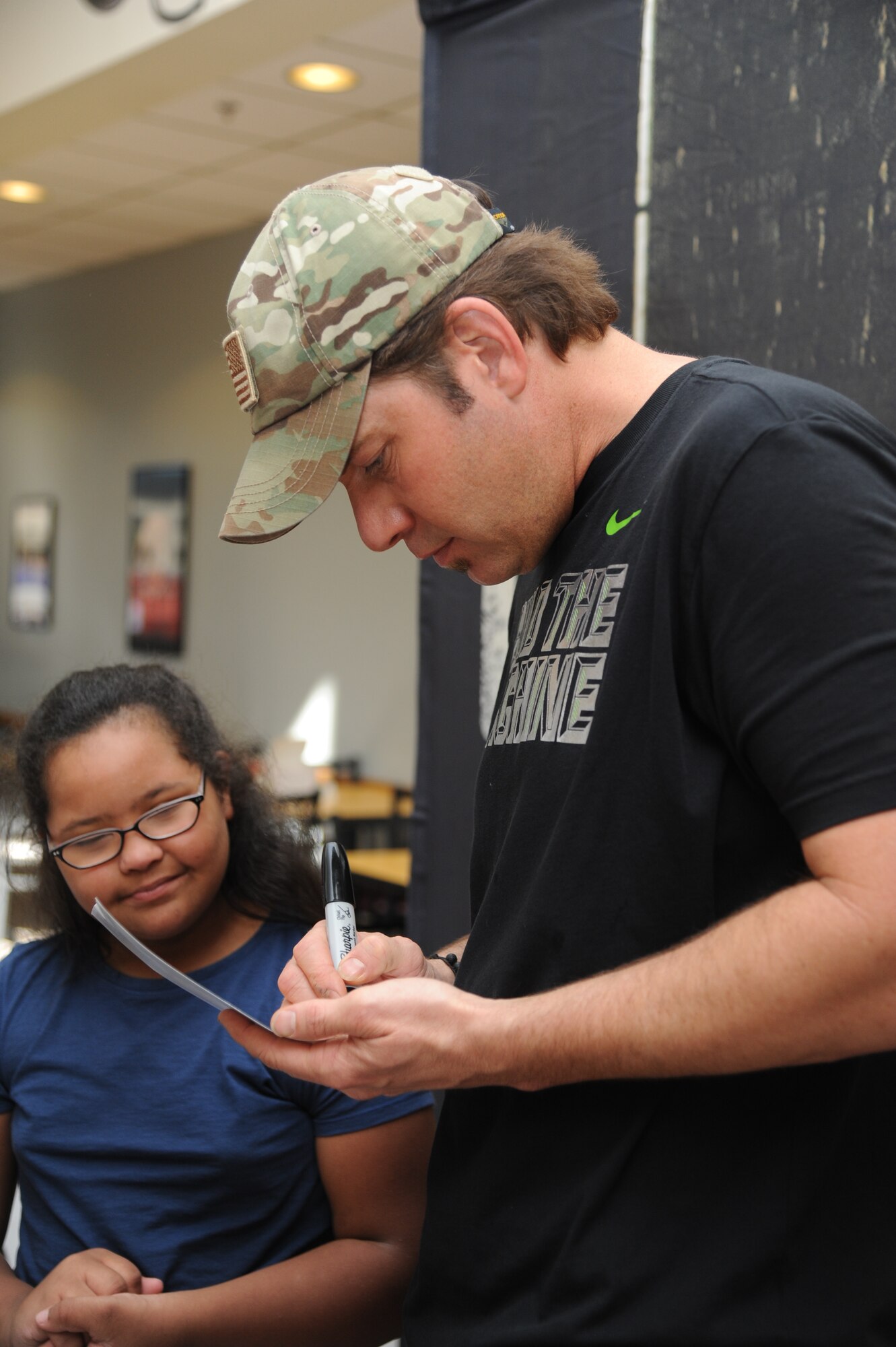 Rodney Atkins, country music singer, autographs a self-portrait during a meet and greet session for the daughter of Chief Master Sgt. Farrell Thomas, 81st Training Wing command chief, and Senior Master Sgt. Lisa Thomas, 81st Force Support Squadron, following a concert performed by Atkins Nov. 2, 2013, at the Magnolia Dining Facility, Keesler Air Force Base, Miss.  Local band Autumn Rise-N also performed.  (U.S. Air Force photo by Kemberly Groue)