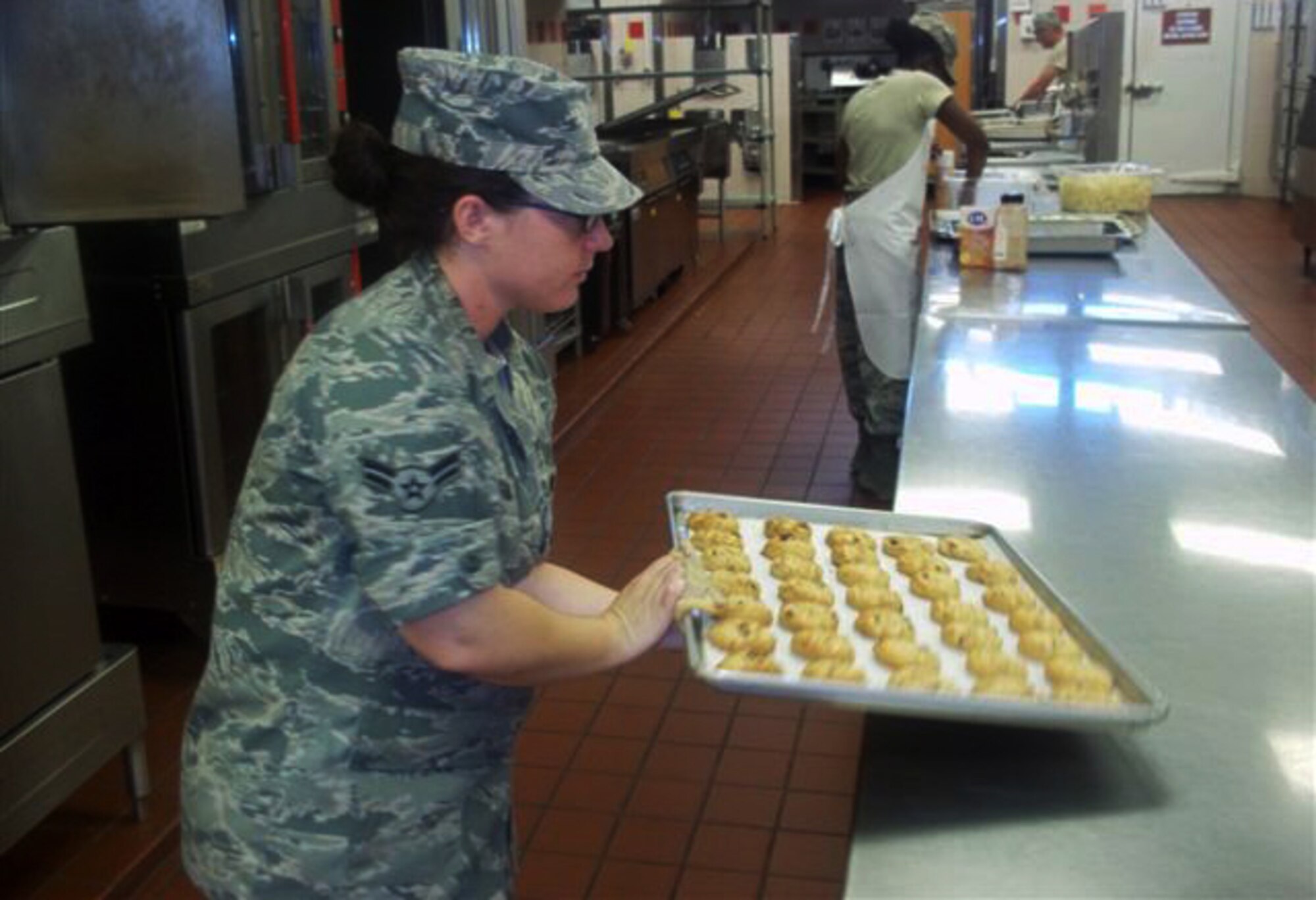 Airman 1st Class Shelbi Newsom, a services specialist with the 188th Force Support Squadron’s Sustainment Services Element, pulls a tray of cookies from the oven at Joint Base Pearl Harbor-Hickam, Hawaii, Sept. 16, 2013. 188th Airmen gained valuable on-the-job training working alongside their active-duty counterparts throughout the base during their two-week long exercise. (U.S. Air National Guard photo by Senior Master Sgt. Brian Vinsant)