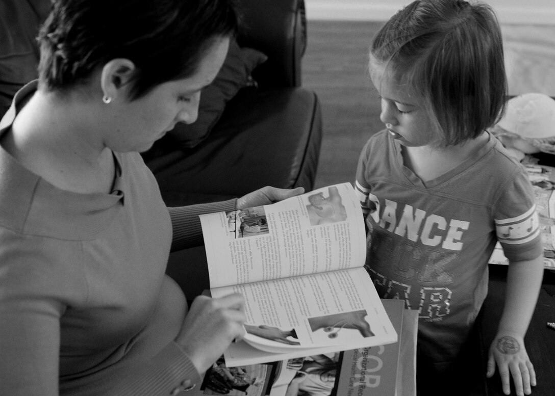 Brandi Jackson shows her daughter Elsie a book about breast cancer in their home Oct. 29, 2013 at Joint Base Andrews, Md. Jackson was diagnosed with cancer nearly one year ago and today is cancer free. (U.S. Air Force Photo/ Staff Sgt. Nichelle Anderson)