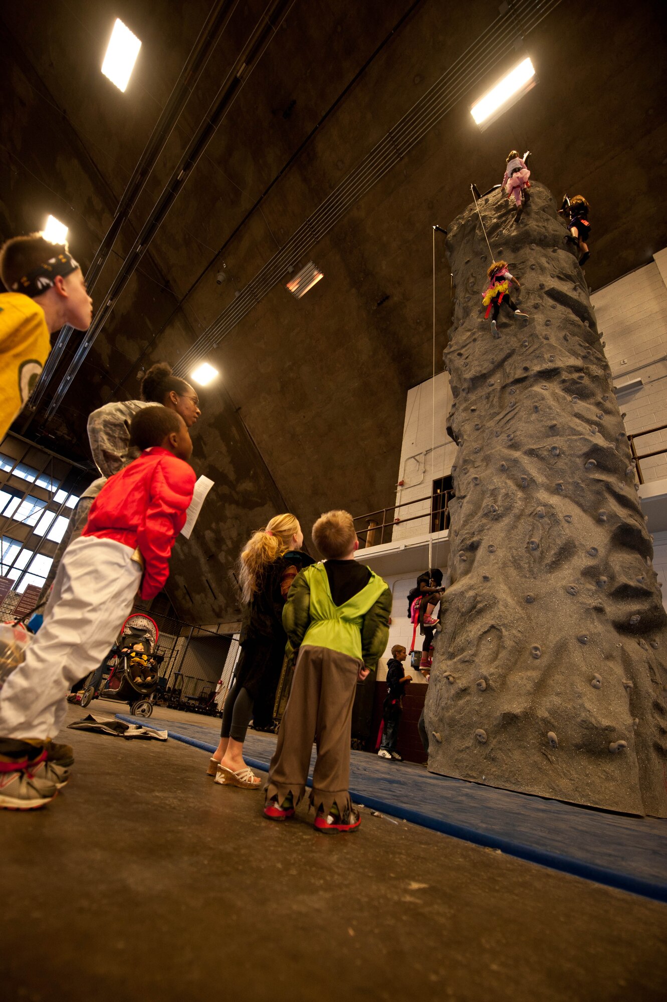 Children climb a rock wall during the Fall Festival hosted by 28th Bomb Wing Chapel in the Pride Hangar at Ellsworth Air Force Base, S.D., Oct. 31, 2013. The festival featured a number of different games and activities including face painting, inflatable castles and costume contests. (U.S. Air Force photo by Senior Airman Class Zachary Hada/Released)