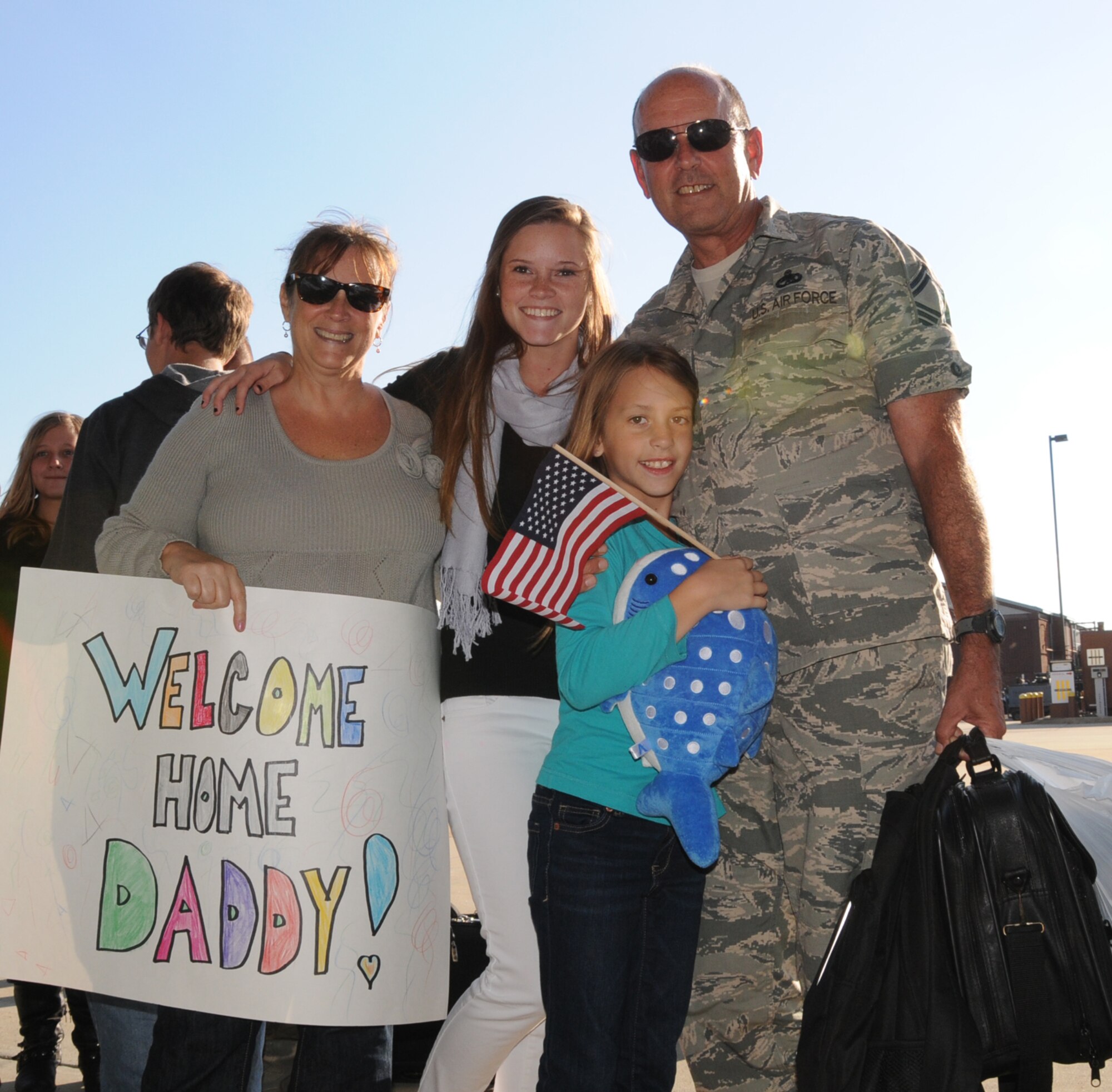 The Joyce family takes time for a portrait during the homecoming for U.S. Air Force Senior Master Sgt. William K. Joyce, 192D Fighter Wing aircraft maintenance superintendent following his deployment to Kadena Air Base, Japan, October 23, 2013.  More than 200 Airmen from the192D Fighter Wing and the 27th Fighter Squadron outfitted with the F-22 Raptor, were assigned to the U.S. Pacific Command as part of a Theater Security Package rotation.  TSP deployments provide stability and security while allowing units to integrate with U.S. and Japanese forces. (U.S. Air National Guard photo by Master Sgt. Carlos J. Claudio/Released)