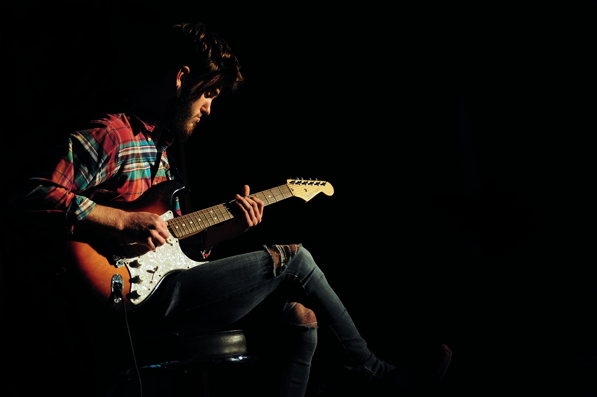 Keyton Daniels, one of the musical guests and Incirlik Unit High School senior, plays his guitar during a set change at the Saturday Night Live Incirlik 2 comedy show Nov. 2, 2013, at Incirlik Air Base, Turkey. In addition to playing guitar for the event Daniels also sang with his musical guest partner Muge Gerena. (U.S. Air Force illustration by Airman 1st Class Nicole Sikorski/Released)