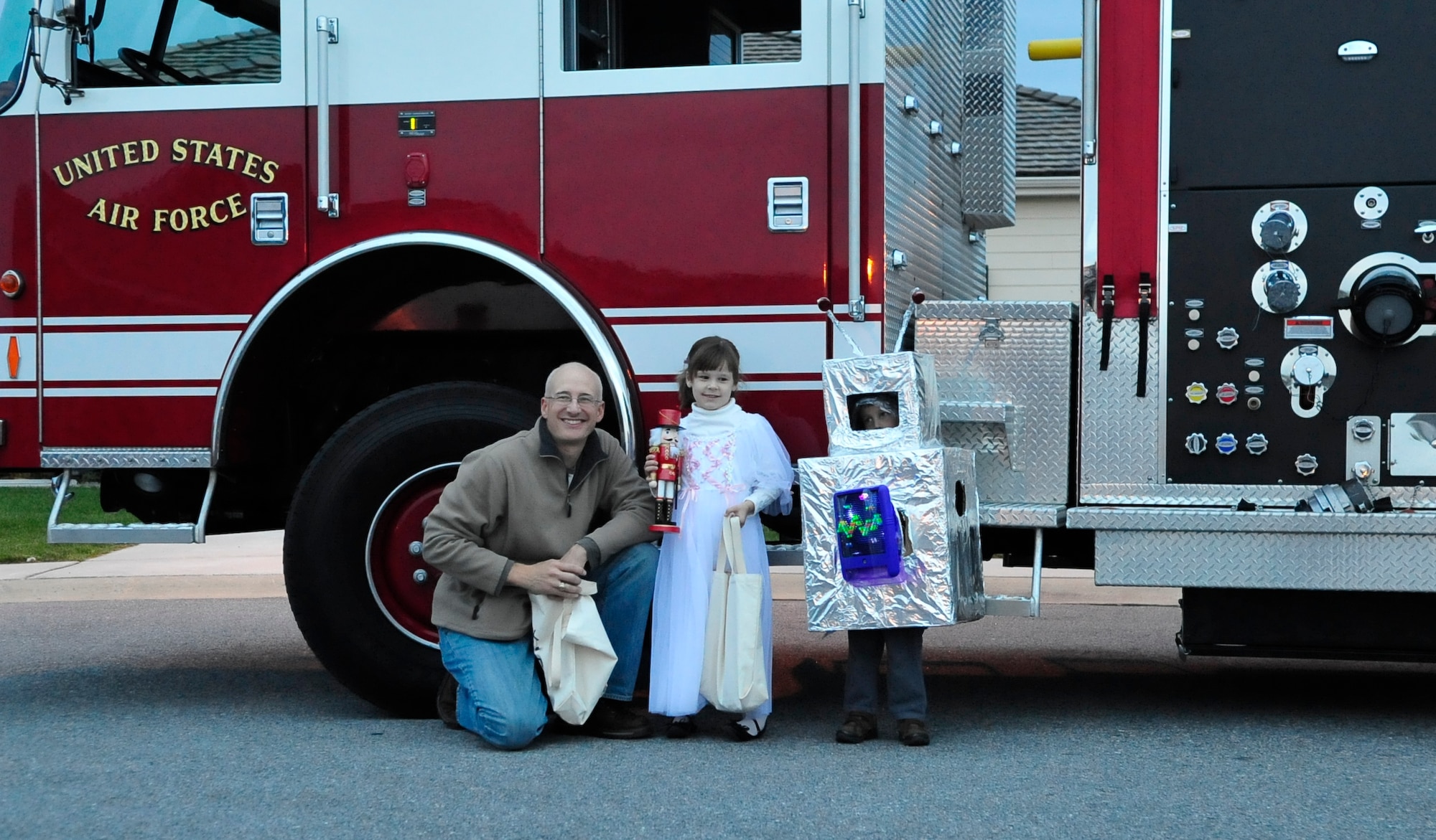 Lt. Col. Scott Bryant, 436th Civil Engineer Squadron commander, poses with his children Scott and Emily  in front of a base fire truck Oct. 31, 2013, at Dover Air Force Base, Del. The 436th CES fire department handed out candy to trick-or-treaters in base housing. (U.S. Air Force photo/Airman 1st Class William Johnson) 