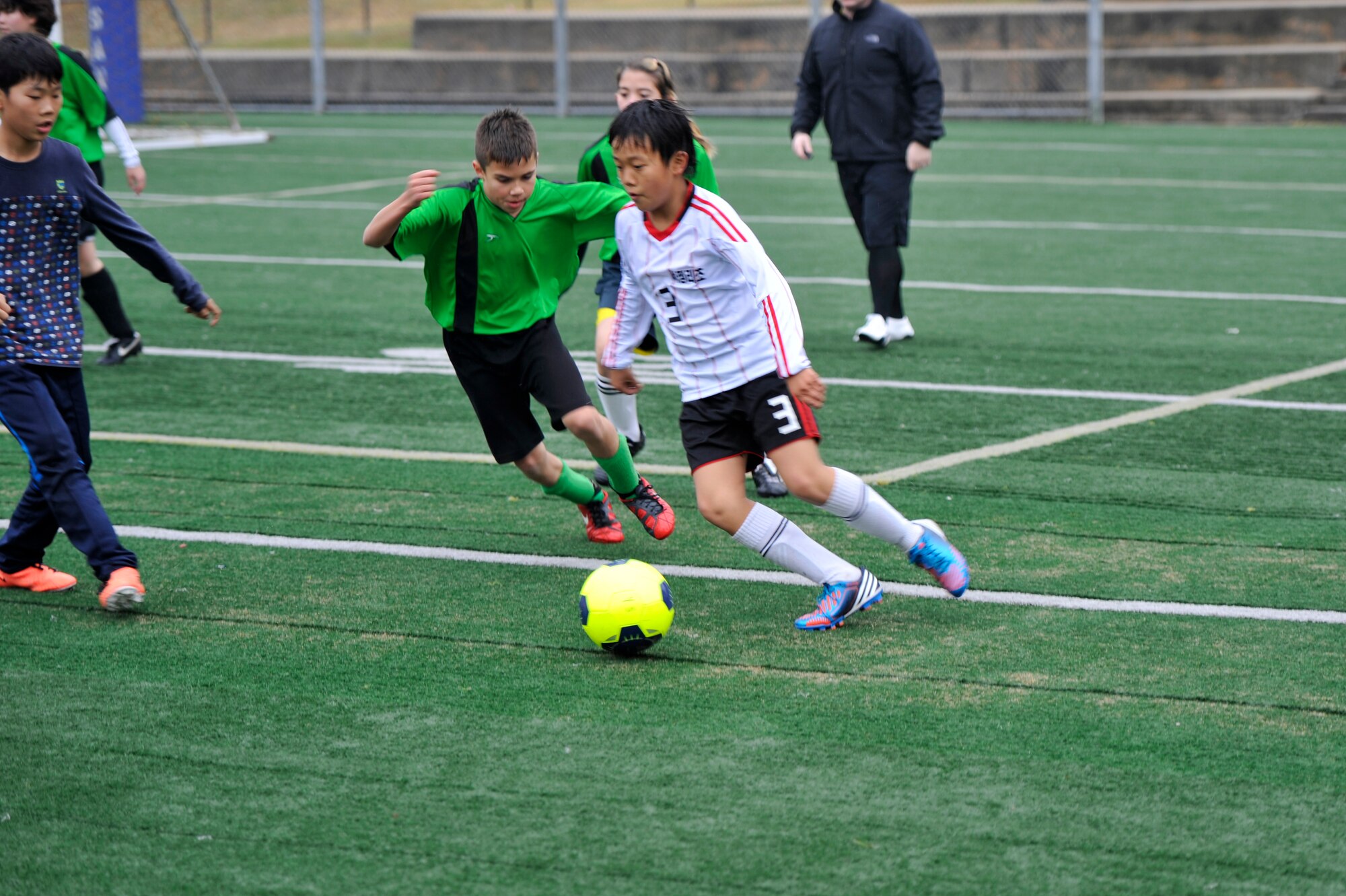 Will Fricke, a forward for the Green Hornets, runs after a Seojungri youth soccer team member to gain control of the ball during a game at Osan Air Base, Republic of Korea, Nov. 2, 2013. Games like these strengthen the bond between members of the local community and the base. (U.S. Air Force photo/Staff Sgt. Emerson Nuñez)
