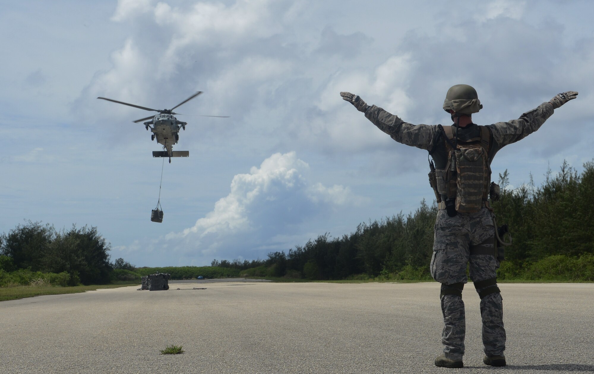 Staff Sgt. Stephen Baker, 736th Security Forces Squadron parachute program manager, directs the helicopter crew to hover during a training exercise Oct. 29, 2013, on Naval Base Guam. The scenario was designed to test the Airmen’s ability to secure and assess a potentially hostile airstrip’s suitability for follow-on Department of Defense aircraft. (U.S. Air Force photo by Airman 1st Class Emily A. Bradley/Released)
