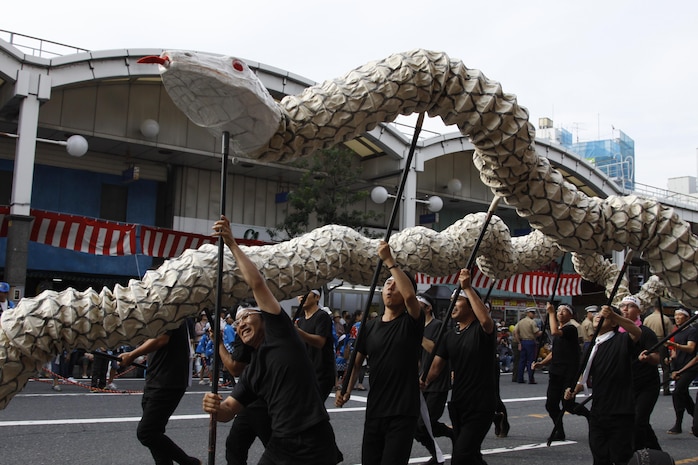 Approximately 12 performers navigate the haribote, or paper mache White Snakes, an Iwakuni-oriented species and designated as a national treasure, through the parade during the 55th Annual Iwakuni Festival in downtown Iwakuni, Oct. 16. When the performers brought the beautifully decorated snakes close enough, parade spectators reached out their hands to touch them. The White Snakes attracted crowds during the parade.