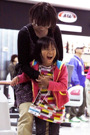 Murakami Naho, 9, a competitive disabled athlete screams with joy and holds onto her mother after bowling a spare at the Strike Zone here Sunday. All of the competitors participated when taken to the bowling alley here, and they all received a medal at the end of the Special Olympics.