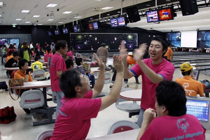 Competitors from Hiroshima Prefecture celebrate their bowling abilities with high-fives at the Strike Zone here Sunday. Athletes from three prefectures including Hiroshima, Yamaguchi and Kumamoto came to the station to compete in soccer, bicycling, disk golf and bowling during the 5th Annual Japanese Special Olympics Sports Day.