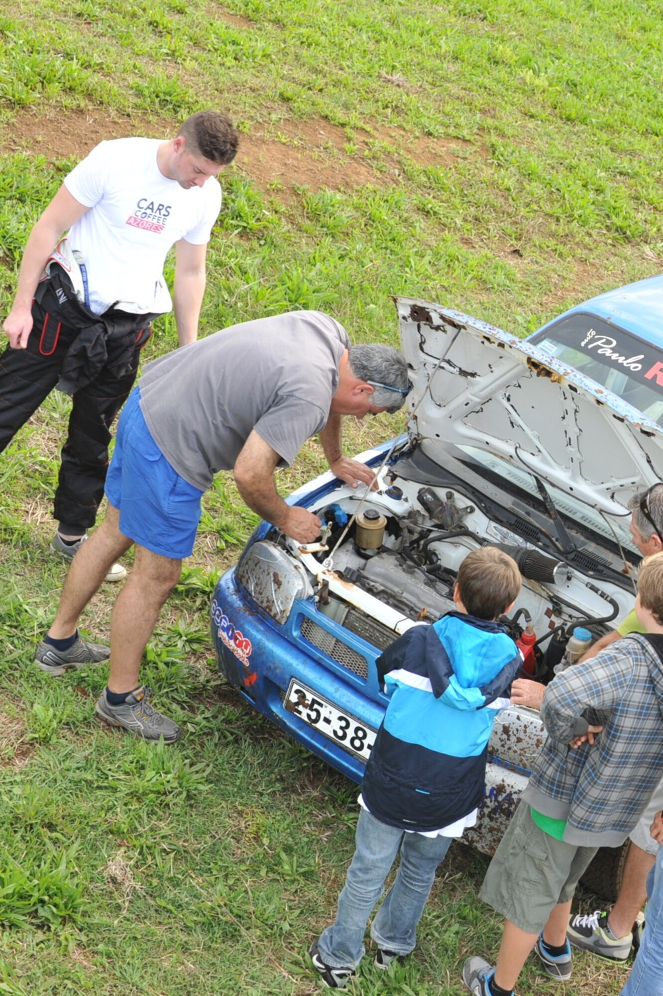 Staff Sgt. Joshua VanHorn, 65th Medical Operations Squadron medical technician, inspects his car with a Portuguese mechanic after a rally race in Praia da Vitoria, Azores. VanHorn participates in car races with Portuguese local nationals and as the only U.S. participant, VanHorn displays an American flag with his last name on his rear driver's-side window.