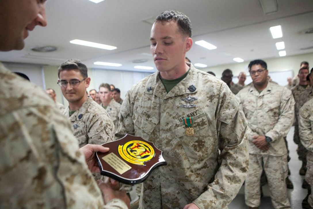 Petty Officer 2nd Class Brandon J. Lovin, the assistant lead petty officer with headquarters and service company, Battalion Landing Team 2nd Battalion, 4th Marines, 31st Marine Expeditionary Unit, and a native of Denver, Colo., receives a plaque and a Navy and Marine Corps Achievement Medal after finishing first overall in the Corpsman Cup here, Oct. 24.