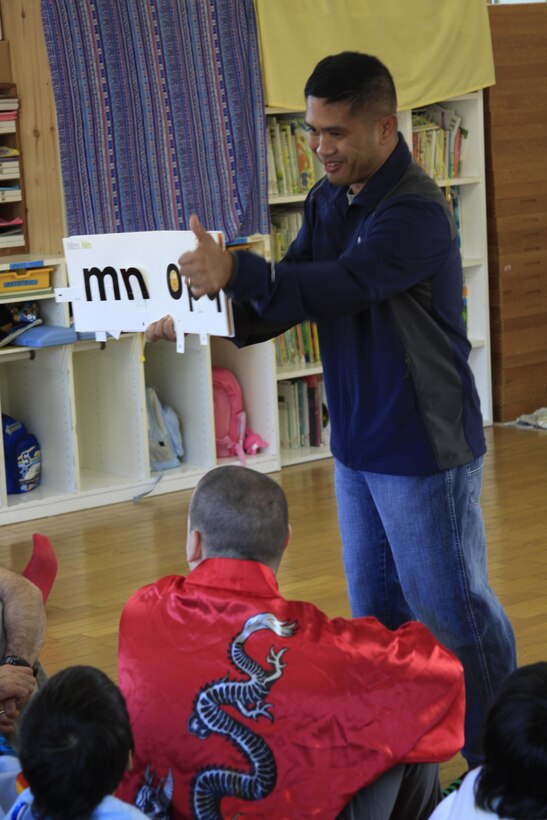 Chief F. B. Dizon, Station chapel religious programmer chief, shows an English alphabet book to children at Midoro Hoiken school Oct. 27. The chapel has been going to Midoro once a month for the past eight years to help Japanese children learn English and to teach the value of exchanging cultures. The chapel goes to Midoro on the fourth Thursday of every month unless a holiday makes it otherwise.