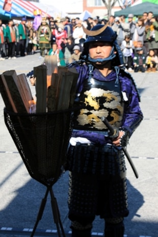 A local Japanese volunteer ignites a traditional kagaribi to start the ceremony of the 22nd Kuragake Castle Festival in Kuga, Iwakuni City, Nov. 20. Event coordinators and local volunteers appreciated the Marines taking time out of their weekend to help reflect on such an important part of the local history.