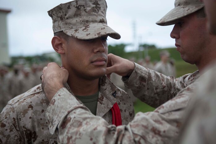 Corporal George A. Caraballo, data technician  with Battalion Landing Team 2nd Battalion, 4th Marines, 31st Marine Expeditionary Unit, Manhattan, N.Y., receives his “blood stripe” during a promotion ceremony here, Nov. 1. The unit adds two unique elements to the Marine Corps’ traditional promotion ceremony in order to highlight the importance of becoming an NCO. To reinforce the responsibility of the new rank, the NCO’s Creed is read, which states the role of NCO leadership, and a 1-inch red stripe is draped over the necks of the new NCO’s.  Dating back to 1849, NCO’s and officers have worn this stripe on the outer edge of their trousers. When the creed is finished, the Marine’s mentors remove the rank of Lance Corporal and promote the Marine to Corporal. BLT 2/4 recently completed a three month tour of the Asia-Pacific region, which included bilateral training with the Australian Defense Force. They are now preparing to return to their home port, Camp Pendleton, Calif., after a successful tour as the 31st MEU’s BLT. 