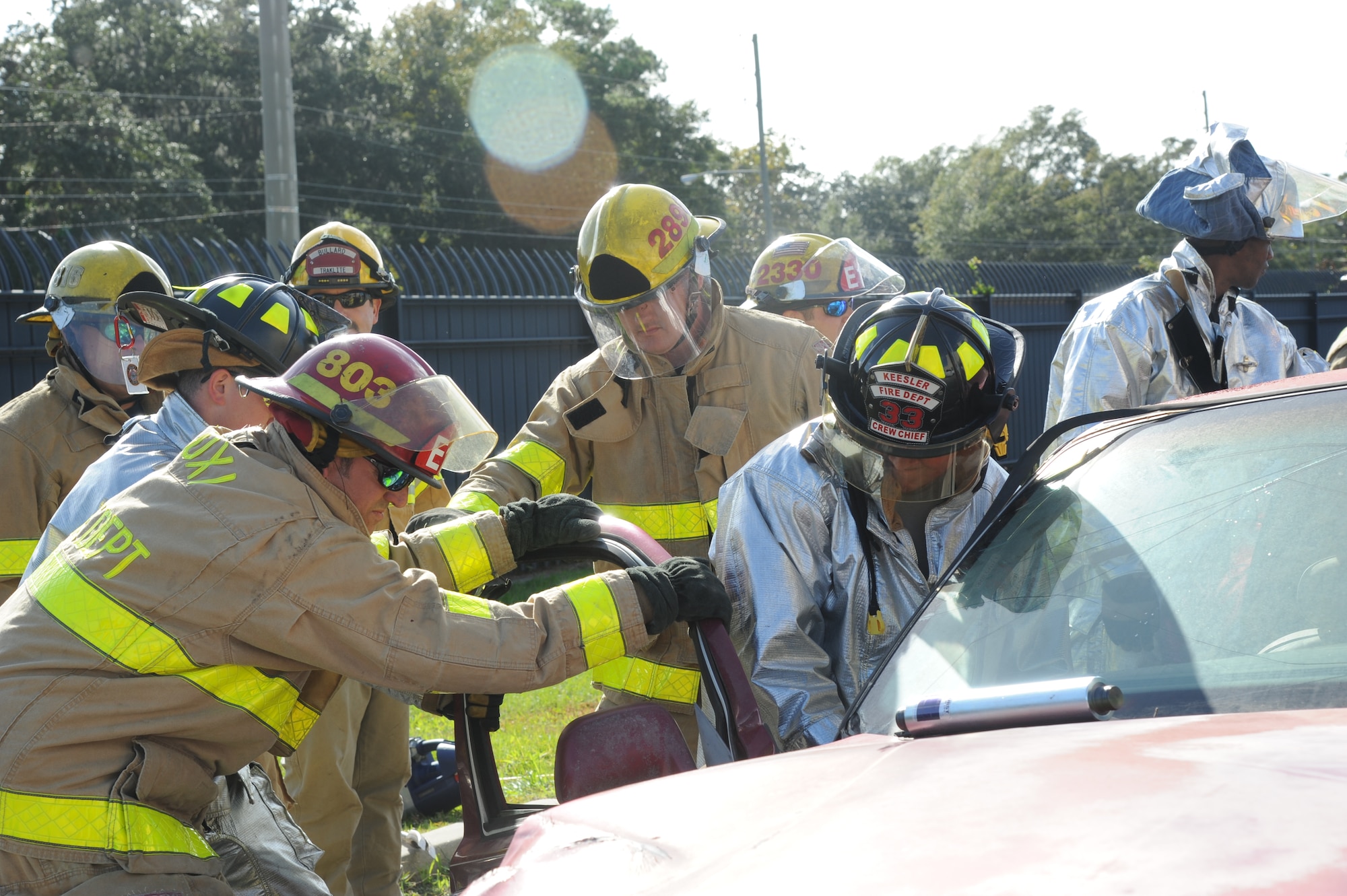 Fire Captain Stephen Dunaway, Biloxi firefighter, holds the vehicle door steady as Staff Sgt. Jared Lott, Keesler Firefighter, uses  new battery powered jaws of life equipment to cut the hinges for victim access as fellow firefighters observe during a two-day joint auto extrication training Nov. 5, 2013, at Keesler Air Force Base, Miss.  Keesler and Biloxi Fire Departments conduct several joint training sessions a year to include: live fire structural burn, auto and a variety of other classes.  (U.S. Air Force photo by Kemberly Groue)