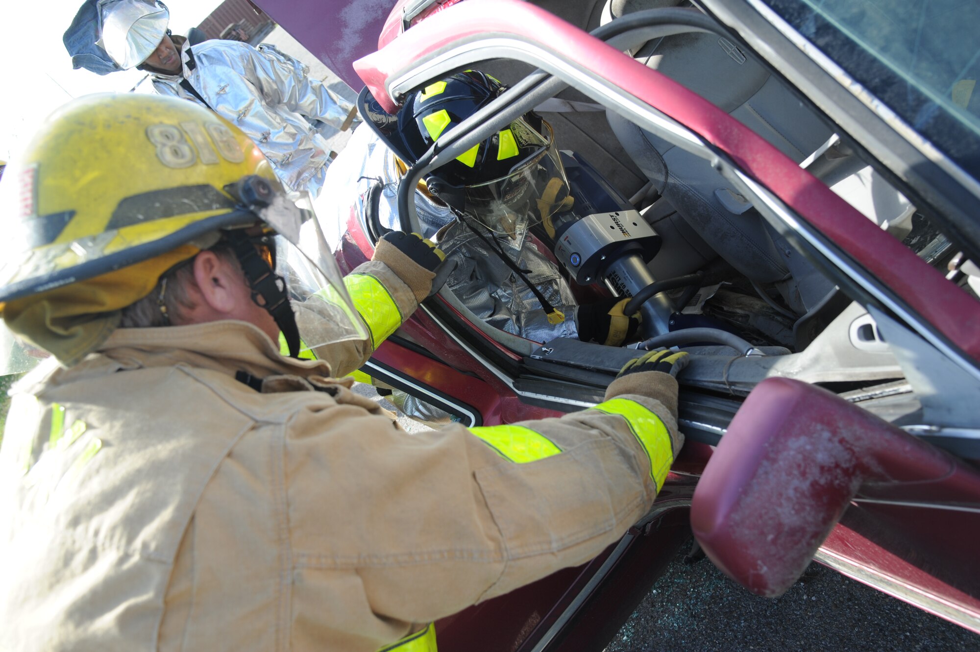 John Massey, Biloxi firefighter, holds the vehicle door steady as Staff Sgt. Jared Lott, Keesler firefighter, uses  new battery powered jaws of life equipment to cut the hinges for victim access as Staff Sgt. Mark Pough, Keesler firefighter, observes during a two-day joint auto extrication training Nov. 5, 2013, at Keesler Air Force Base, Miss.  Keesler and Biloxi Fire Departments conduct several joint training sessions a year to include: live fire structural burn, auto and a variety of other classes.  (U.S. Air Force photo by Kemberly Groue)