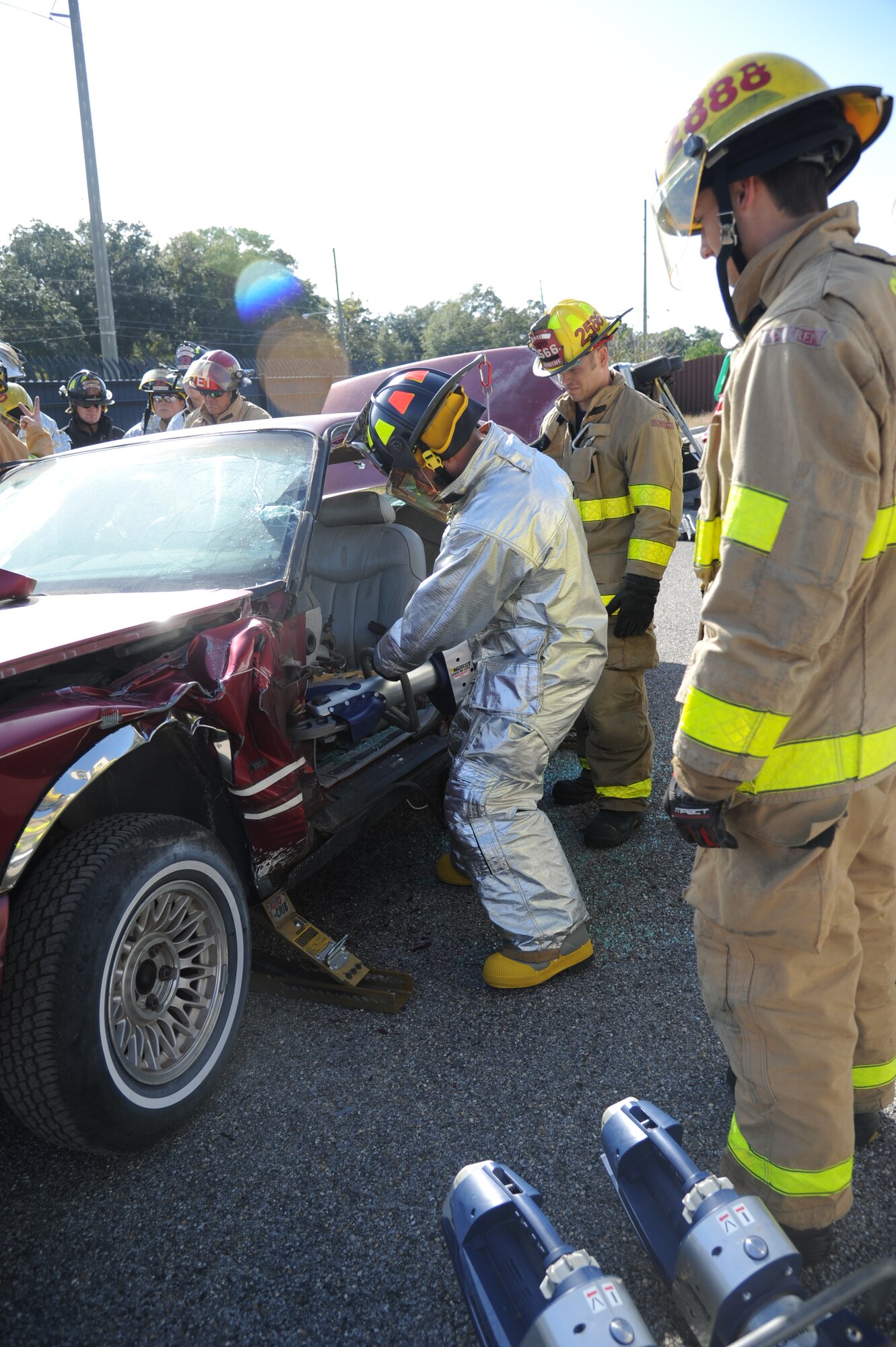 Airman 1st Class Tyler Fisher, Keesler firefighter, uses new powered jaws of life equipment to make a cut into a vehicle to allow the dash to be pushed up as Andy Cosper and Nicholas Dubuisson, Biloxi firefighters, observe during a two-day joint auto extrication training Nov. 5, 2013, at Keesler Air Force Base, Miss. Keesler and Biloxi Fire Departments conduct several joint training sessions a year to include: live fire structural burn, auto and a variety of other classes.  (U.S. Air Force photo by Kemberly Groue)