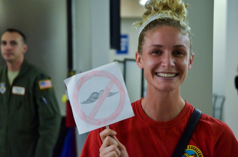 Anne Marie Kemp holds up a “no more mustache” sign hoping to encourage her husband, 14th Airlift Squadron pilot Capt. Ryan Kemp, to shave it off after he returned from his deployment on November 2, 2013 at Joint Base Charleston — Air Base, S.C. (U.S. Air Force photo/Airman 1st Class Michael Reeves)