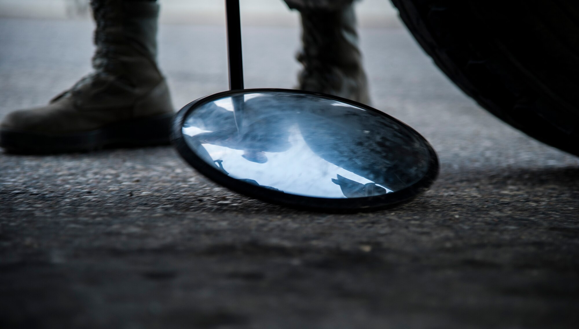 Airman 1st Class Tanner Mansuetti, 5th Security Forces Squadron installation entry controller, checks under a vehicle for any intrusive devises here, Nov. 6, 2013. Mansuetti, is part of a dedicated team of entry controllers charged with front line protection of the installation and its assets. (U.S. Air Force photo/Airman 1st Class Andrew Crawford)