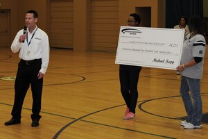 Tim Masheck, National Government Services vice president of health information technology, presents a check for $14,225 to the Langley Air Force Base Boys & Girls Club at the Bethel Manor Youth Center in Yorktown, Va., Nov. 5, 2013. The grant will help establish the Triple Play program as a daily event for children at the center. (U.S. Air Force photo by Staff Sgt. Jarad A. Denton/Released)