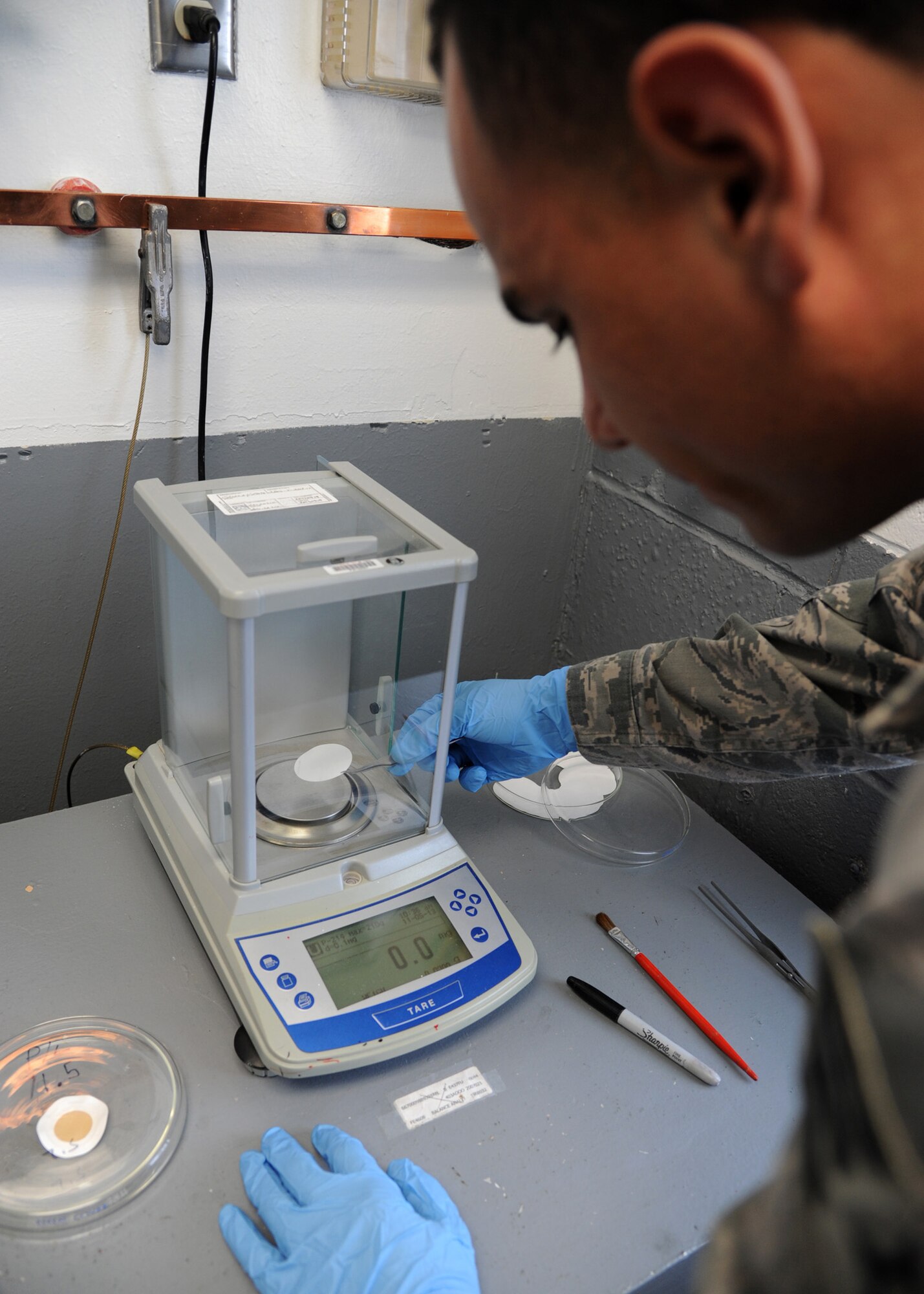 Senior Airman Christian Ramirez, 2nd Logistics Readiness Squadron fuels laboratory technician, places a membrane filter on the analytical balance scale on Barksdale Air Force Base, La., Nov. 5, 2013. The scale is used to weigh the filter paper before and after sampling, giving the amount of particulate found in one gallon of fuel. (U.S. Air Force photo/Senior Airman Joseph A. Pagán Jr.)