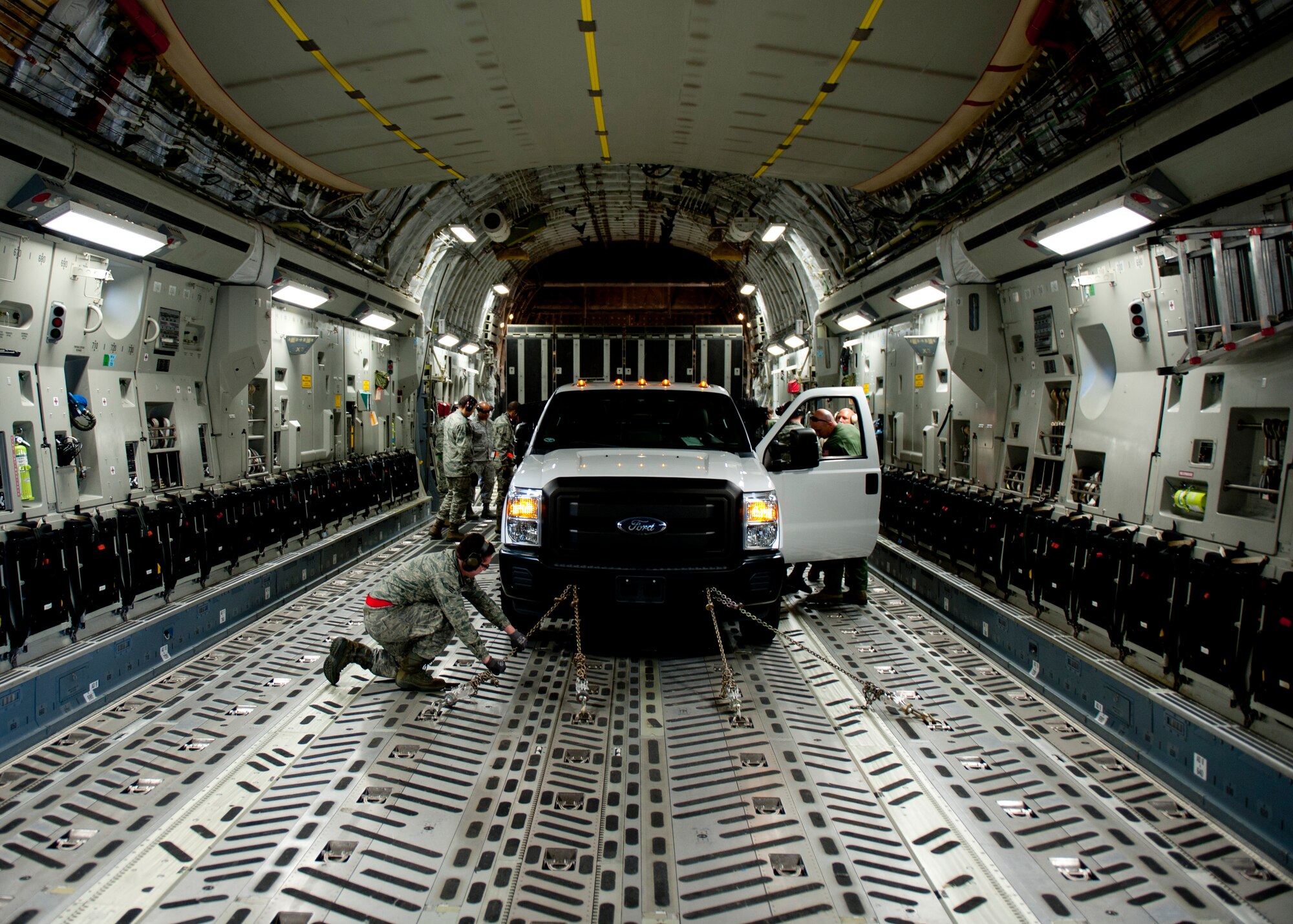U.S. Air Force Senior Airman Scott Miller, 71st Aerial Port Squadron ramp specialist, chains down a truck inside of a C-17 Globemaster III during a training mission at Langley Air Force Base, Va., Nov. 2, 2013. The 71st APS is an Air Force Reserve unit that provides logistical functions to ports of debarkation, to include passenger and cargo processing, airdrop rigging and preparing cargo for flight.  (U.S. Air Force photo by Staff Sgt. John D. Strong II/Released)