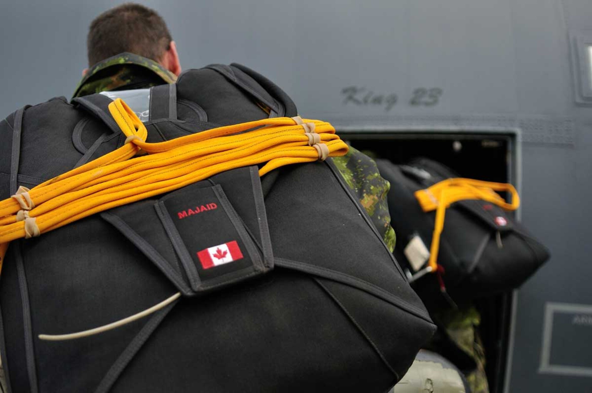 Members of the Canadian Army Advanced Warfare Centre (CAAWC), carry their parachutes on board an Alaska Air National Guard C-130 aircraft during an Arctic Search and Rescue Exercise (Arctic SAREX) on Oct. 30, 2013. The exercise involved a parachute jump to a simulated major air disaster (MAJAID) scenario along with drops of specialized survival equipment needed to sustain survivors in the arctic climate. The Army parachutists were participating alongside Canadian Armed Forces Search and Rescue technicians and United States Air Force para-rescuers during the SAREX, involving a response to simulated airliner crash along the Alaska/Yukon border. Cross-border SAREXs are conducted regularly to ensure both Canadian and American SAR personnel are familiar with each others' operations in the event of an emergency response involving crews from both the Canadian Armed Forces and U.S. military. (Image by Capt Trevor Reid, 19 Wing Public Affairs)