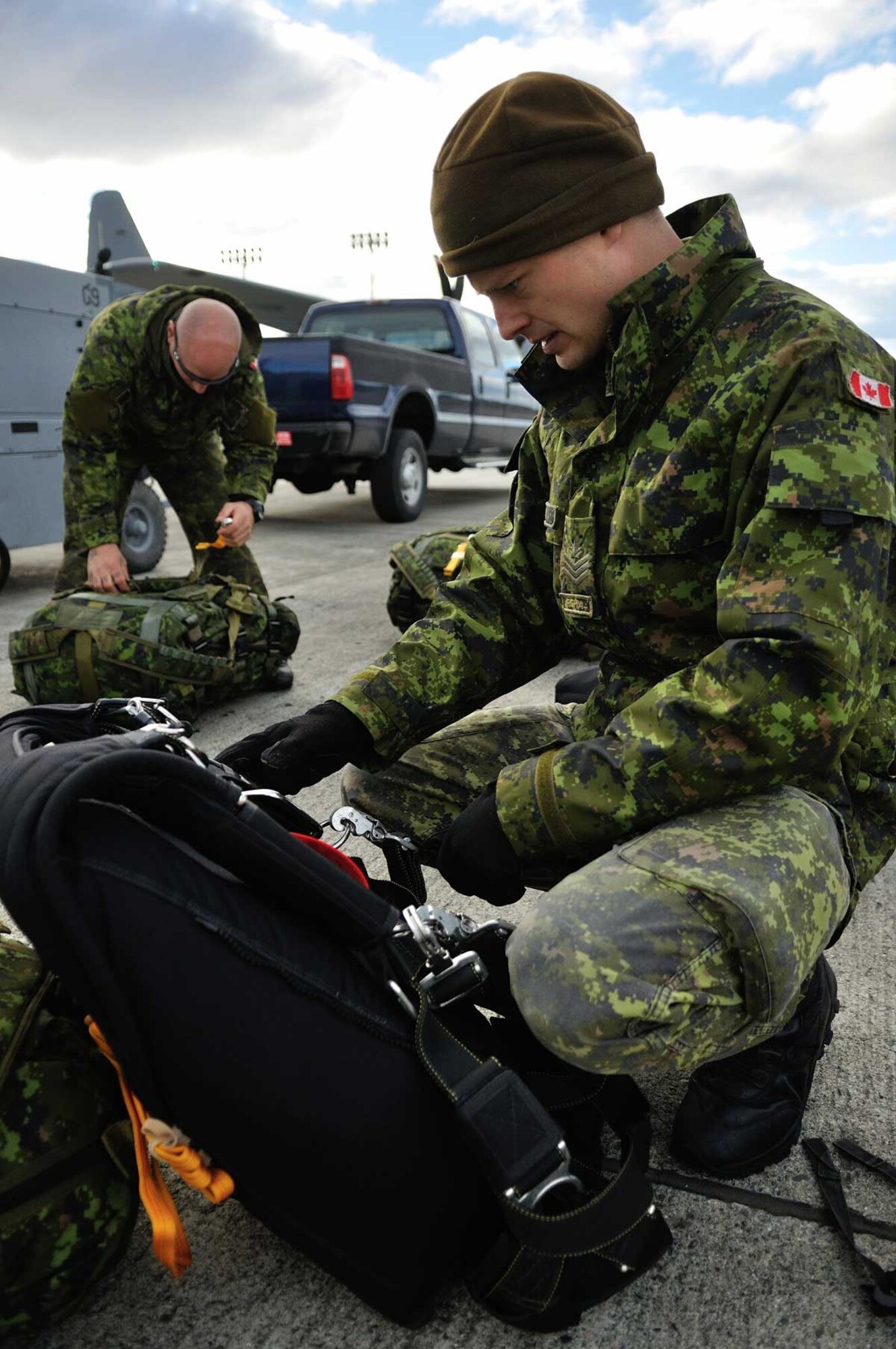 Sgt. Joel Dunville of the Canadian Army Advanced Warfare Centre (CAAWC) prepares his parachute and drop bag for a jump into the scene of a major air disaster search and rescue exercise. Dunville and six other members of the CAAWC flew on board an Alaska Air National Guard C-130 aircraft as part of the joint Canada/U.S. Arctic Search and Rescue Exercise (Arctic SAREX) on Oct. 30, 2013. The Army parachutists were participating alongside Canadian Armed Forces Search and Rescue technicians and United States Air Force para-rescuers during the SAREX, involving a response to simulated airliner crash along the Alaska/Yukon border. Cross-border SAREXs are conducted regularly to ensure both Canadian and American SAR personnel are familiar with each other’s operations in the event of an emergency response involving crews from both the Canadian Armed Forces and U.S. military. (Image by Capt. Trevor Reid, 19 Wing Public Affairs)
