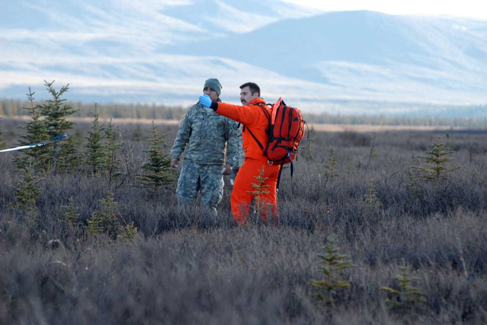 A Canadian Search and Rescue Technician points out the Causality Collection Point to a wounded soldier at Donnelly Training Area, October 30. The soldier is a role player in the Joint Task Force-Alaska, Alaska National Guard, U.S. Army Alaska, Canadian Joint Operations Command Arctic Search and Rescue Exercise held here and at Joint Base Elmendorf-Richardson. Canadian and U.S. Search and Rescue assets jumped into the simulated crash site and immediately began stabilizing and providing treatment to the wounded until support was available to transport the wounded to a medical treatment facility. This exercise aimed to increase the collective interoperability between the U.S. and Canada. (Photo by U.S. Army public affairs)