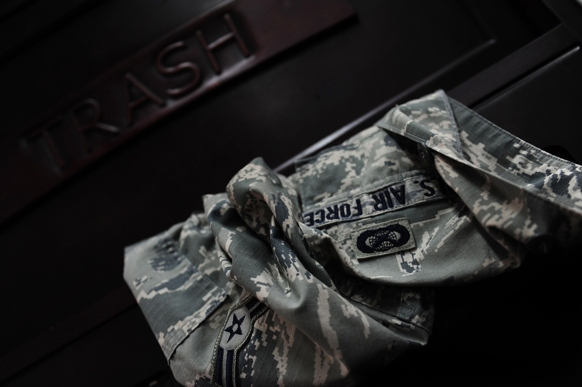 An improperly discarded Airman Battle Uniform sits in a trash can Nov. 5, 2013, Incirlik Air Base, Turkey.  All military uniforms should be disposed of by removing all patches, rank insignia and functional badges followed by either shredding or burning the uniform.  (U.S. Air Force photo by Airman 1st Class Nicole Sikorski/Released) 