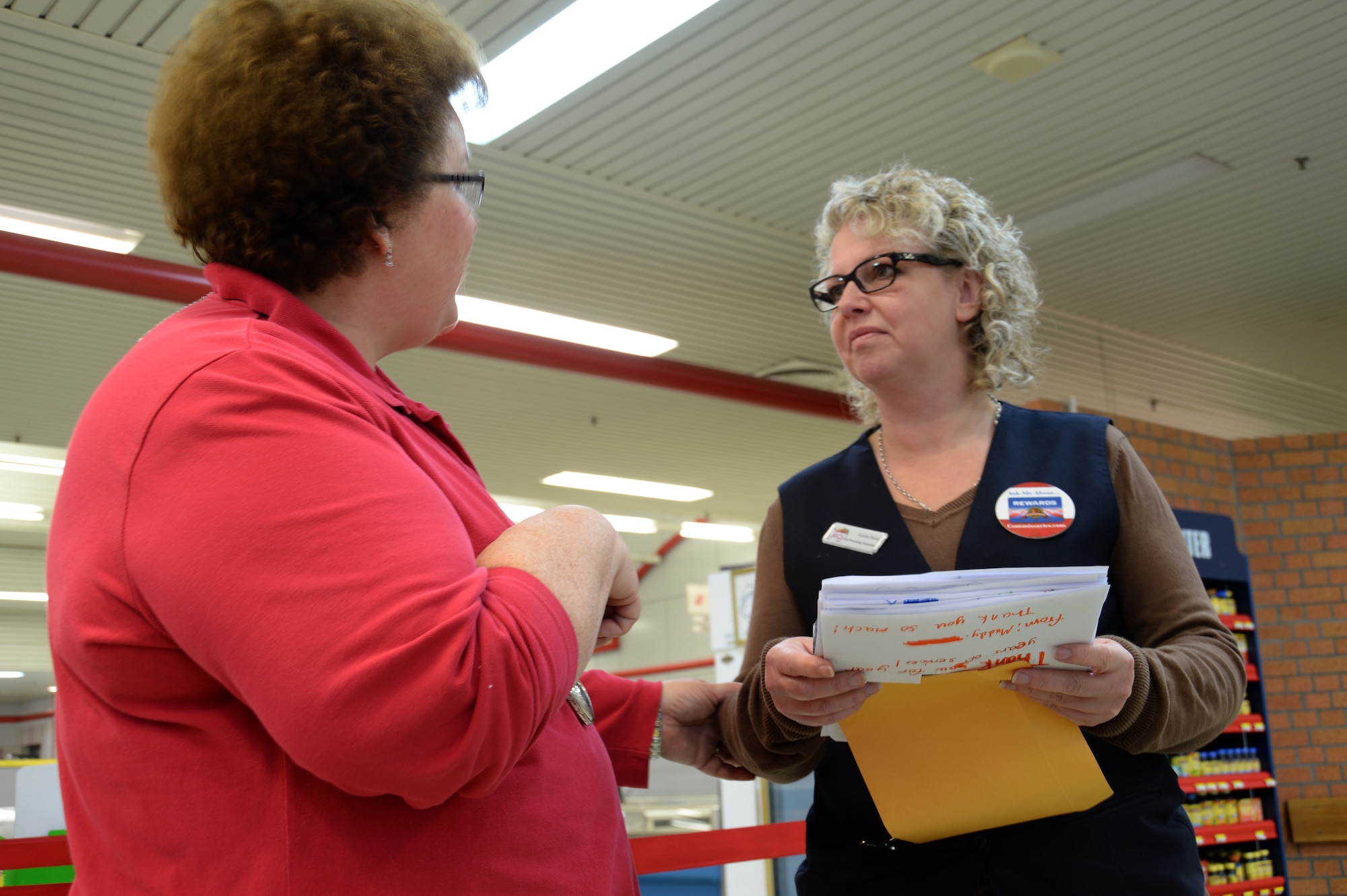 BITBURG BASE ANNEX, Germany --- Karola Hooker, a cash processing technician at the Bitburg Commissary, right, listens after Elizabeth Rowe, a teacher at Bitburg elementary school, left, handed her “thank you” cards during the last day of the commissary’s operations Oct. 31, 2013. Rowe’s elementary school class made the cards for the commissary’s staff to thank them for their years of service to the community.  (U.S. Air Force photo by Senior Airman Joe W. McFadden / Released)