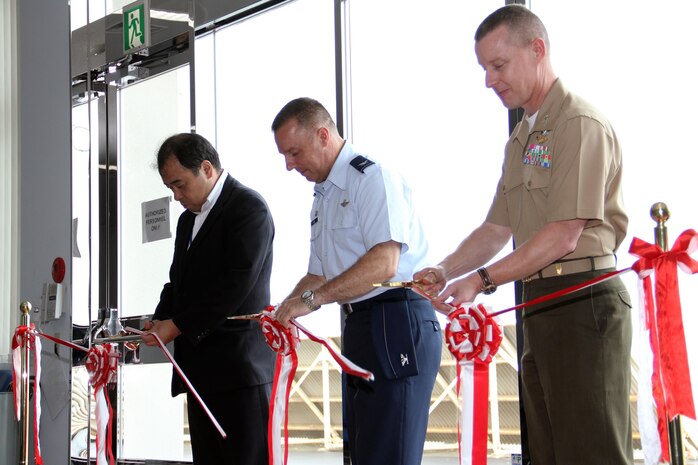 Masayoshi Tatsumi, Chugoku-Shikoku Defense Bureau director general (left), Col. Robert Ricci, 515 Air Mobility Operations Group commander and Col. James C. Stewart, station commanding officer, cut a ribbon at the Air Mobility Command passenger terminal here during the terminal’s official opening ceremony here Aug. 19. Planning for construction started in 2001. Actual construction began in 2006 and finished in 2010.