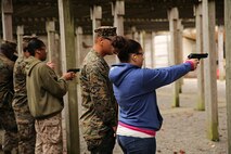 Marines with 2nd Supply Battalion, Combat Logistics Regiment 25, 2nd Marine Logistics Group stand with their wives as they fire pistols at a range during a Jane Wayne Day event aboard Camp Lejeune, N.C., Nov. 7, 2013. Other events included navigating an obstacle course, participating in the Marine Corps Martial Arts Program and receiving a combat lifesaver course. (U.S. Marine Corps photo by Lance Cpl. Shawn Valosin)