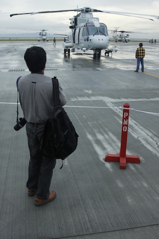 A Japanese off-base resident watches as a Mitsubishi SH-60J prepares its preflight routine for a flight demonstration during the Japanese Maritime Self-Defense Force Iwakuni Air Base Festival here Sunday. This event allows for members of JMSDF to show and familiarize interested community members with their facilities, equipment and service members. The event also gave JMSDF families a boots-on-the-ground avenue to further understand the self-defense force. The JMSDF command here sponsored the event. The SH-60J has cruise speed of 276 kilometers per hour and carries a three crew member team.