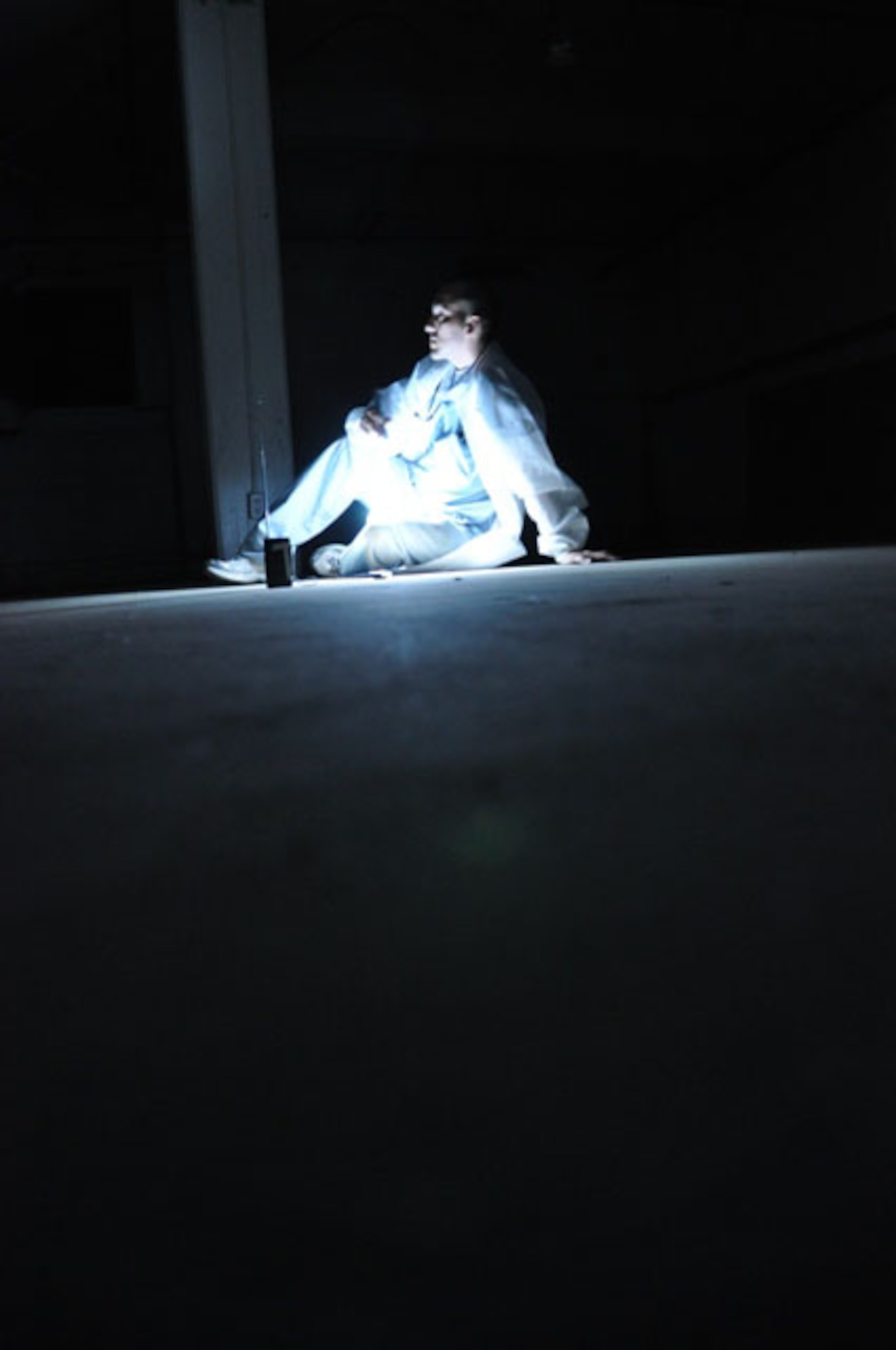Senior Airman Jose Mora, 452nd Aerospace Medicine Squadron, wears a lab coat and stethoscope during an April 20, 2013 paranormal investigation, hoping it would put spirits at ease while investigating a former medical facility at March Field. Here Mora sits in the dark asking questions to prompt replies through an Electronic Voice Phonomina recorder. (U.S. Air Force photo/Linda Welz)