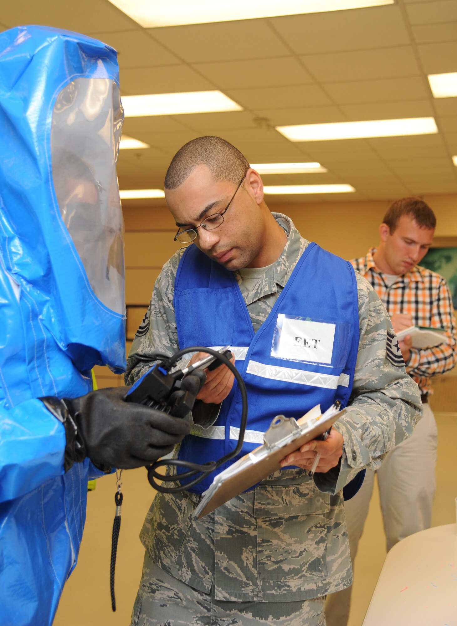 Tech. Sgt. Chris Bowens, 81st AMDS exercise evaluation team member, gives exercise input information to Airman 1st Class Von Fernan Carios, 81st Aerospace Medicine Squadron bioenvironmental engineering technician, while identifying a mock “simulation positive” for phosphoric acid esters during a Chemical, Biological, Radiological, Nuclear, and high-yield Explosive exercise scenario Nov. 6, 2013, at Keesler Air Force Base, Miss.  The Force Protection Condition exercise scenario included a suspect posing as a driver making a delivery to the Locker House and spraying a chemical on a group of Airmen as they were assisting him with unloading the packages from the truck.  Immediately, the Airmen simulated receiving eye irritations, excessive sweating, chest pain, choking, and vomiting from exposure to the chemical.  (U.S. Air Force photo by Kemberly Groue)