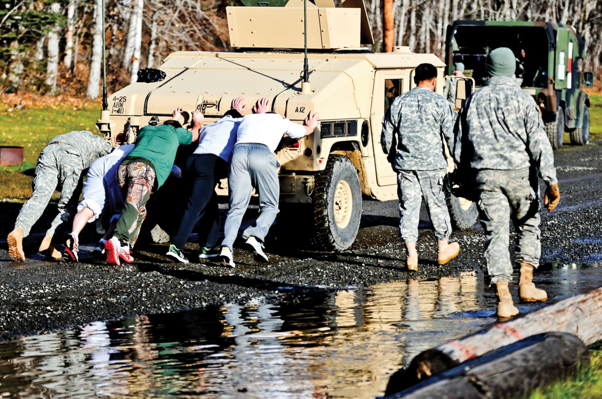 Hockey players with the University of Alaska Anchorage (Seawolves) and a Paratrooper with U.S. Army Alaska push a Humvee along a gravel path Oct. 25, 2013, at Joint Base Elmendorf-Richardson, Alaska. The hockey team visited JBER for a day filled with competitive physical fitness activities designed to enhance teamwork and leadership skills. (U.S. Army photo by Staff Sgt. Jeffrey Smith/Released)