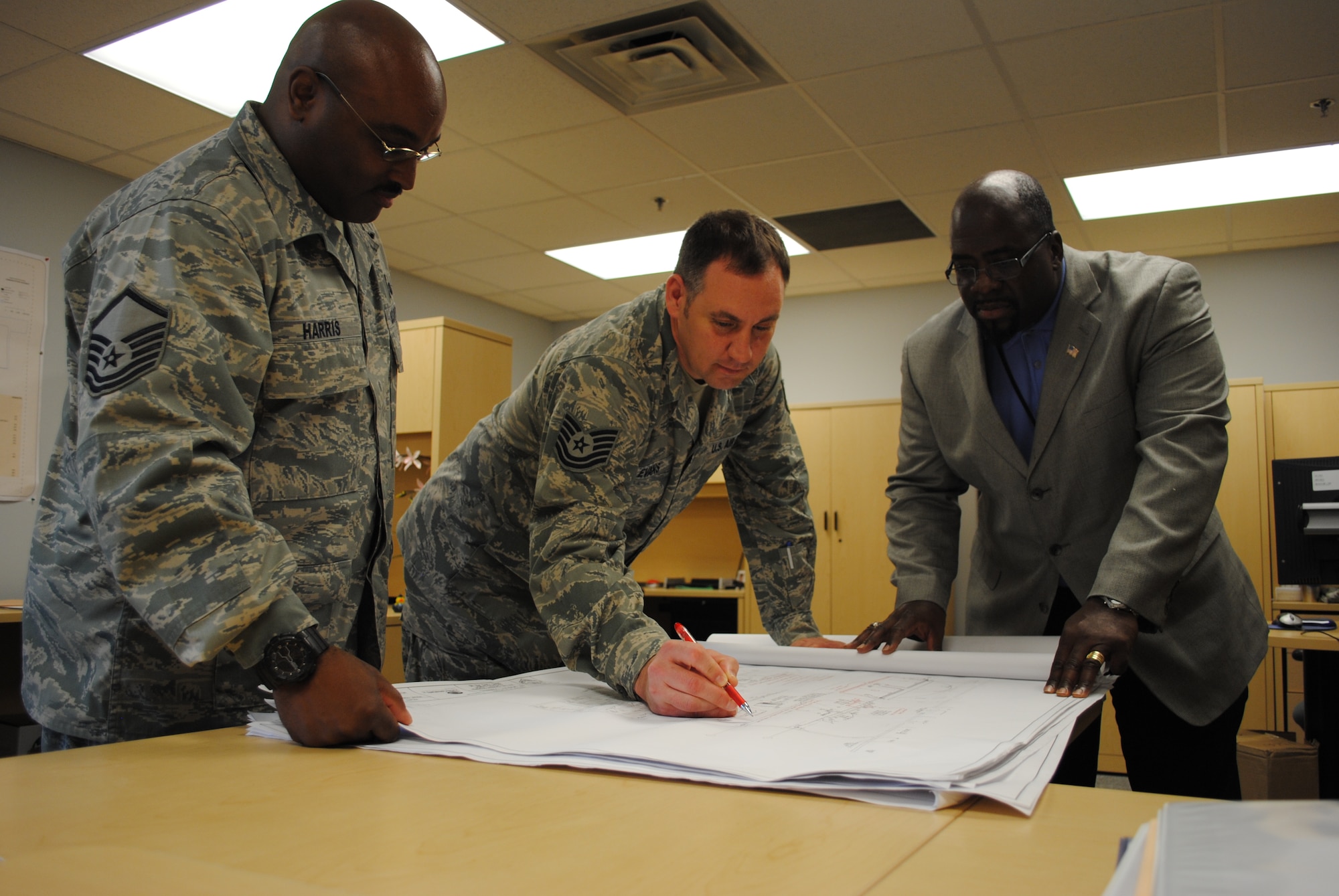 Master Sgt. Jermaine Harris, 319th Communications Squadron Plans and Programs flight superintendent and Tech. Sgt. David Evans, 319th CSX project planner exam blueprints for a building with 319th CS chief of Plans, Programs and Resources, Ronald Cooper, May 31, 2013, on Grand Forks Air Force Base, N.D.  The 319th CSX flight is in charge of reviewing blueprints for all projects on base involving communication systems such fiber optic cables and network connection ports for printers and fax machines. (U.S. Air Force photo/Staff Sgt. Luis Loza Gutierrez)

