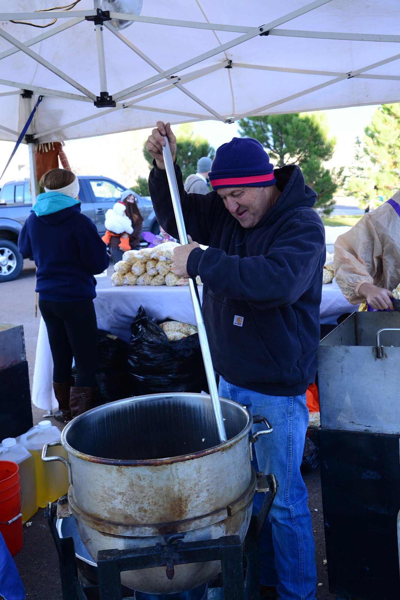 Don Jenkins, owner of 4 Lazy J Kettlecorn, in Bog Sandy, Mont., stirs up a fresh batch of kettlecorn for trick-or-treaters at the commanders’ Halloween party Oct. 31. More than 200 bags of free kettlecorn were given out during the event. (U.S. Air Force photo/Airman 1st Class Collin Schmidt)