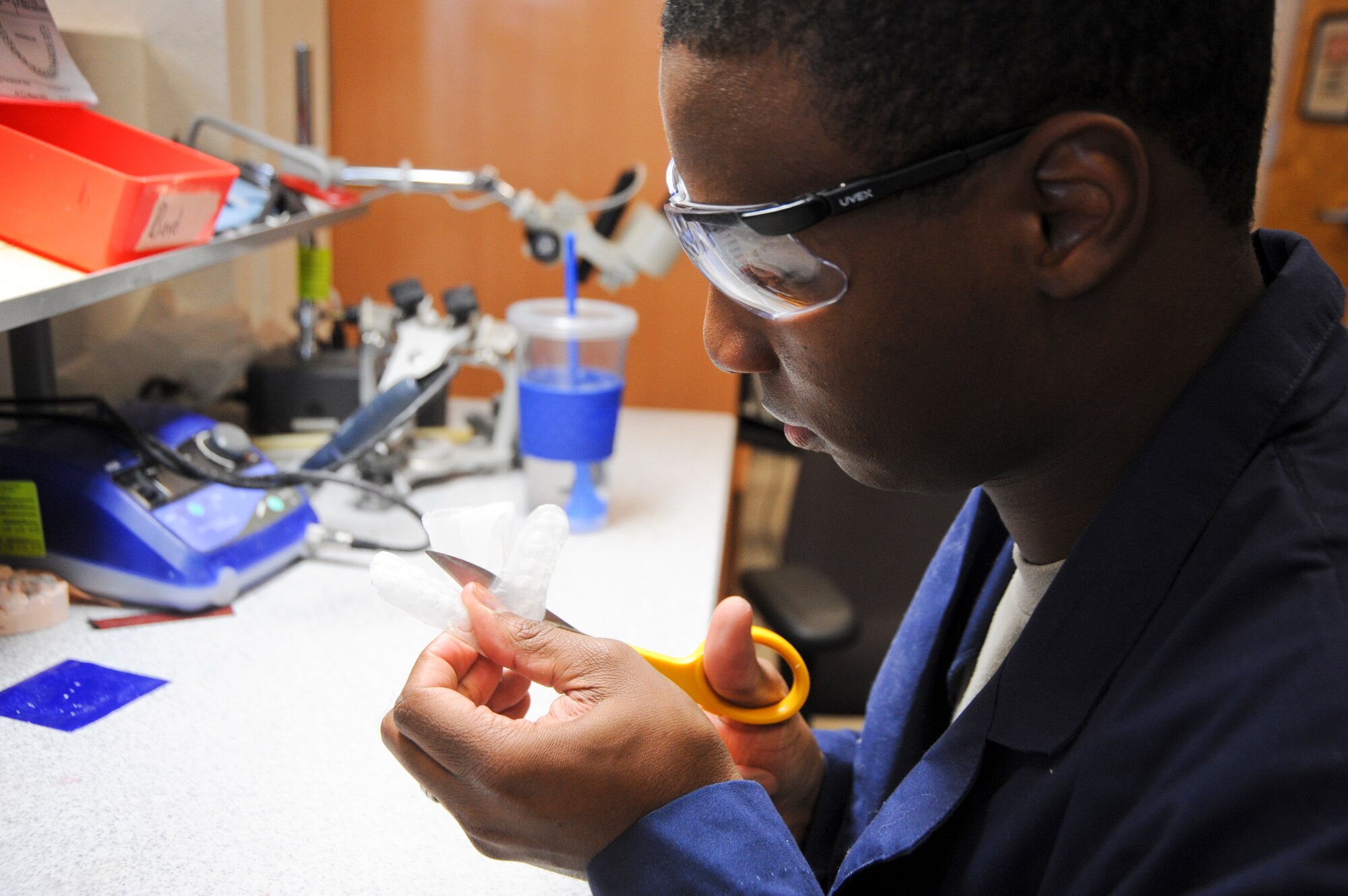 U.S. Air Force Senior Airman Tarell Walker, 355th Medical Group dental laboratory technician, cuts a mouth guard at Davis-Monthan Air Force Base, Ariz., Oct. 24, 2013. There are three types of mouth guards: a ready-made (stock) mouth guard, a “boil and bite’ guard and a custom mouth guard that is made by a dentist. (U.S. Air Force Senior Airman Sivan Veazie/Released)