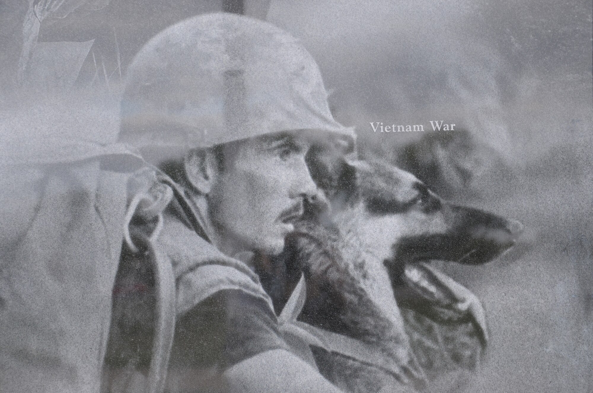 A image of a handler with his dog during the Vietnam War was part of collection that create a montage that is etched onto the face of the wall at the Military Working Dog Teams’ National Monument which was revealed Oct. 28, 2013 at Joint Base San Antonio-Lackland, Texas. There was also a statue of an Airman that was accompanied by four dog statues. (U.S. Air Force photo by Airman 1st Class Krystal M. Jeffers/Released)