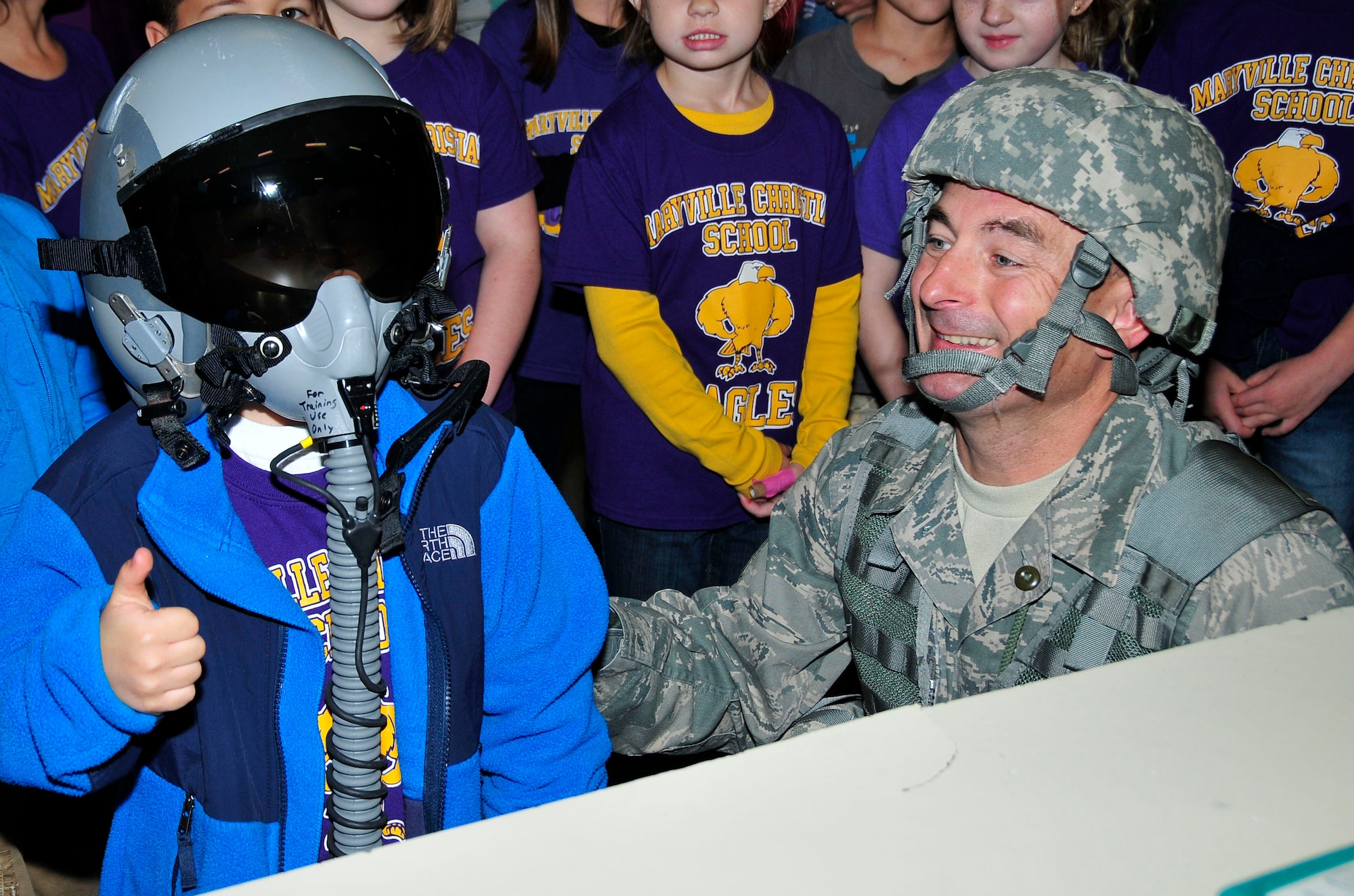 Tech. Sgt. Jon Crawford, 134 ARW Aircrew Flight Equipment Specialist, smiles as Caden Jones, a Maryville Christian School 1st grader, gives a thumbs up while wearing pilot training gear.  Caden's father, Master Sgt. Eric Jones, is a Boom Operator with the 134th Air Refueling Wing.  (U.S. Air National Guard photo by Master Sgt. Kendra M. Owenby, 134 ARW Public Affairs)