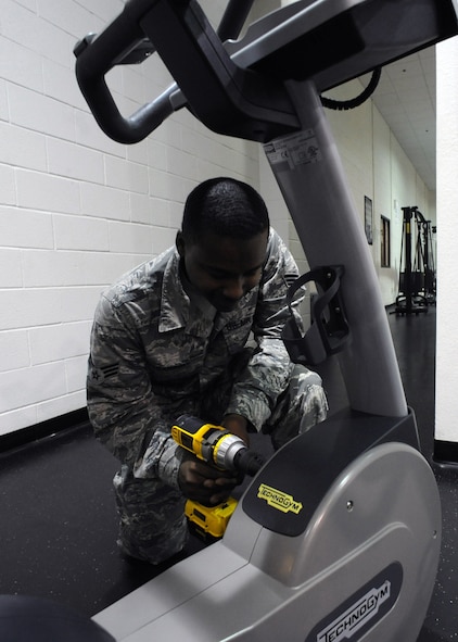 U.S. Air Force Senior Airman Damon Carroll, 7th Force Support Squadron, repairs a stationary bike Oct. 30, 2013, at the fitness center on Dyess Air Force Base, Texas. While working at the fitness center, Carroll ensures all equipment is working correctly so that it is safe to operate. (U.S. Air Force photo by Senior Airman Shannon Hall/Released)
