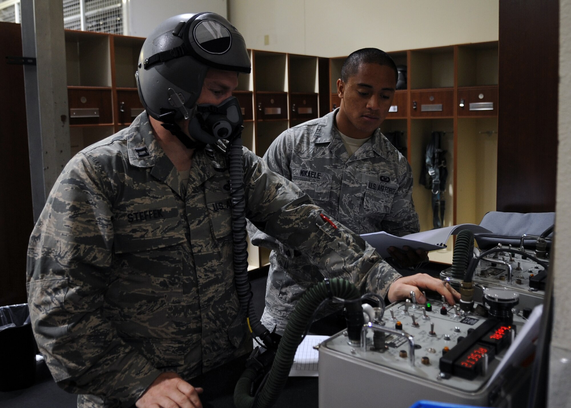 U.S. Air Force Airman 1st Class Pesamino Mikaele, right, assists Capt. Craig Steffak, both from the 7th Operations Support Squadron, with pre-flighting his flight helmet and mask Oct. 29, 2013, at Dyess Air Force Base, Texas. This procedure ensures aircrew member’s microphone works correctly and the oxygen mask fits properly prior to flight. (U.S. Air Force photo by Senior Airman Shannon Hall/Released)