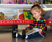 HANSCOM AIR FORCE BASE, Mass. -- Two-year old Emma Robey flips through a book at the Combined Federal Campaign’s Reach Out and Read Scholastic Book Fair held in the 66th Medical Squadron lobby Nov. 6. Reach Out and Read is an evidence-based nonprofit organization of medical providers who promote early literacy and school readiness in pediatric exam rooms nationwide by giving new books to children and advice to parents about the importance of reading aloud. (U.S. Air Force photo by Linda LaBonte Britt)