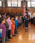 HANSCOM AIR FORCE BASE, Mass. – Col. Lester A. Weilacher, 66th Air Base Group commander, and Chief Master Sgt. Mitchell Balutski, Hanscom Air Force Base senior enlisted advisor, along with students and staff from the Hanscom Middle School, stand during the National Anthem as Bedford High School Junior ROTC members present the colors as part of Veterans Day ceremony Nov. 4 at the school. Weilacher spoke to students about Veterans Day and what it means to him. He also presented awards and citizenship certificates to students. (U.S. Air Force photo by Rick Berry)