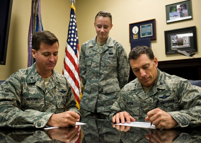 Brig. Gen. Charles Moore (left), 57th Wing commander, and  Col. Craig Baker, 57th Wing vice commander fill out the Combined Federal Campaign pledge forms as Airman 1st Class Chyann Walsh, 57th Wing knowledge operator and CFC program coordinator, observes Nov. 7, 2013, at Nellis Air Force Base, Nev. The CFC is the world’s largest annual workplace charity campaign, with almost 200 CFC campaigns throughout the country and overseas, raising millions of dollars each year. Pledges made by federal civilian and military donors during the campaign season support eligible non-profit organizations by providing health and human service benefits throughout the world. Due to the recent government shutdown many CFC events were put on hold or cancelled. The Director of the U.S. Office of Personnel Management extended the CFC solicitation period from Dec. 15, 2013, until Jan. 15, 2014.  (U.S. Air Force photo by Airman 1st Class Jason Couillard)