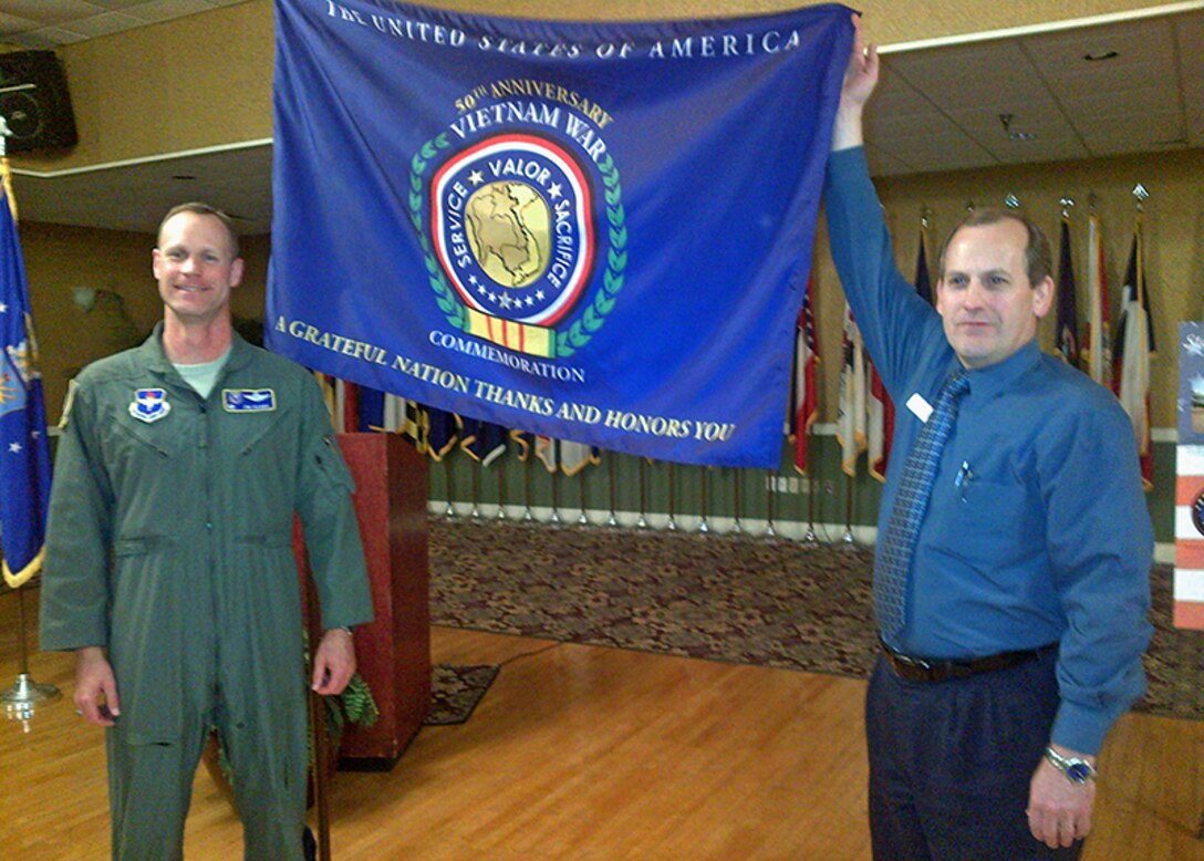 Col. Jim Sears, 14th Flying Training Wing Commander receives the flag commemorating the 50th anniversary of the Vietnam War from Greg Runyon, Assistant Store Director of the Columbus AFB Commissary at the conclusion of the Base Community Council luncheon Nov. 8 at the Columbus Club.  Runyon asked the wing to carry the flag in the City of Columbus Veterans Day parade on Nov. 9. (U.S. Air Force Photo/Sonic Johnson)